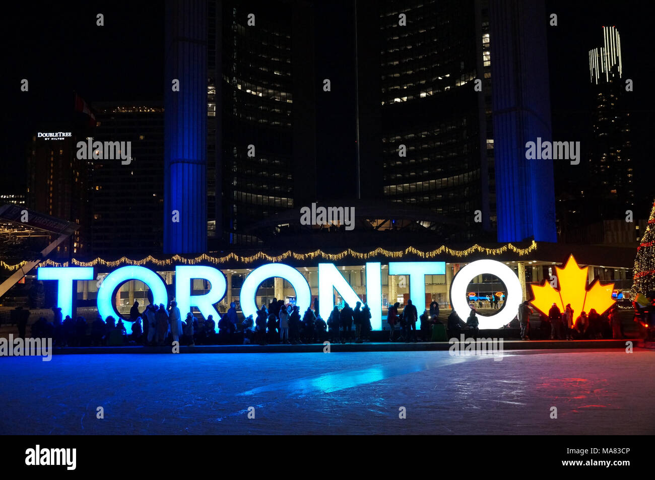 TORONTO, Canada - 2018-01-01 : Persone nella parte anteriore del segno di Toronto con albero di Natale nella notte vista lungo la pista di pattinaggio sulla centrale di Nathan P Foto Stock