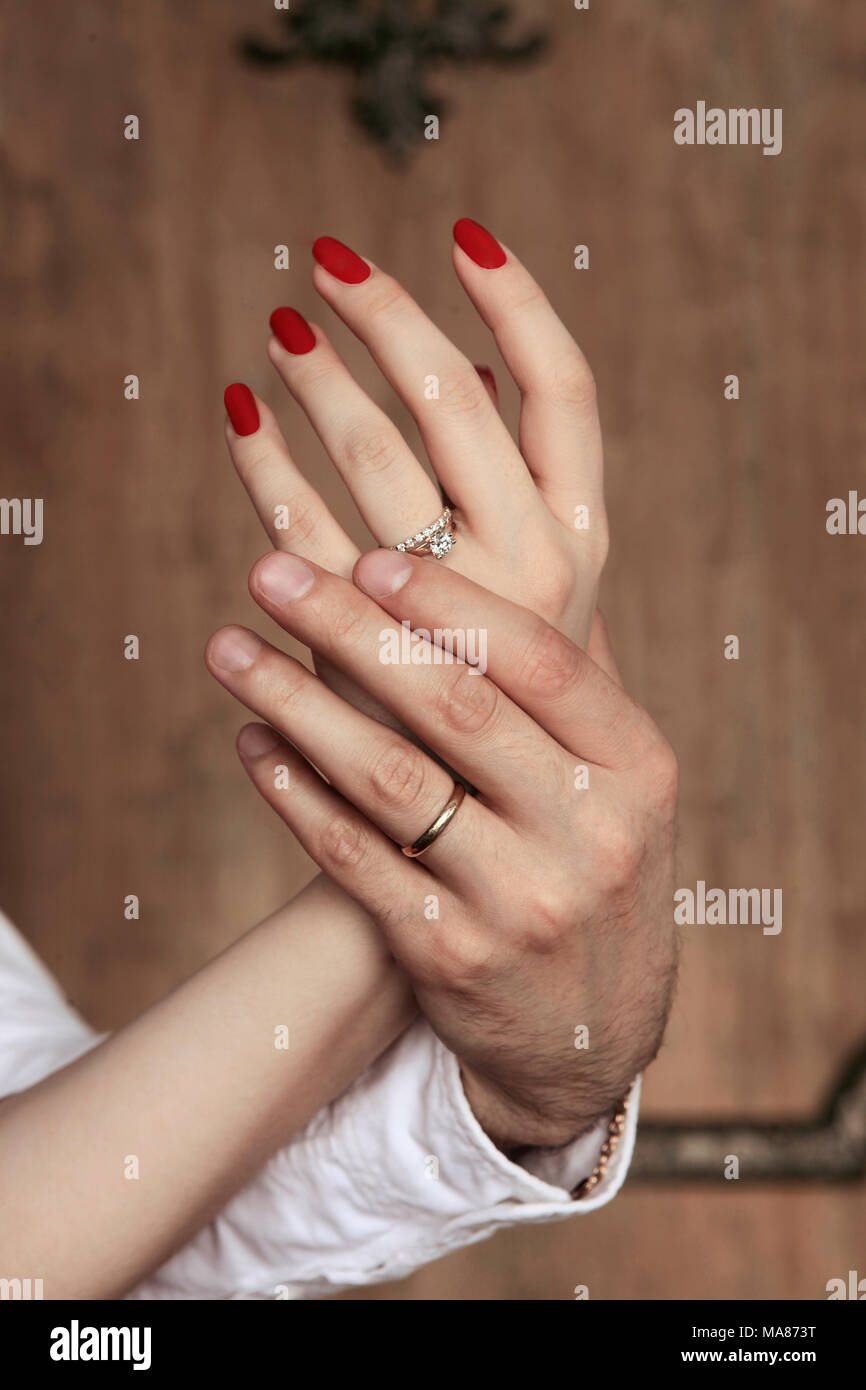 Mani femminili nelle mani dell'uomo su un sfondo di legno Foto Stock