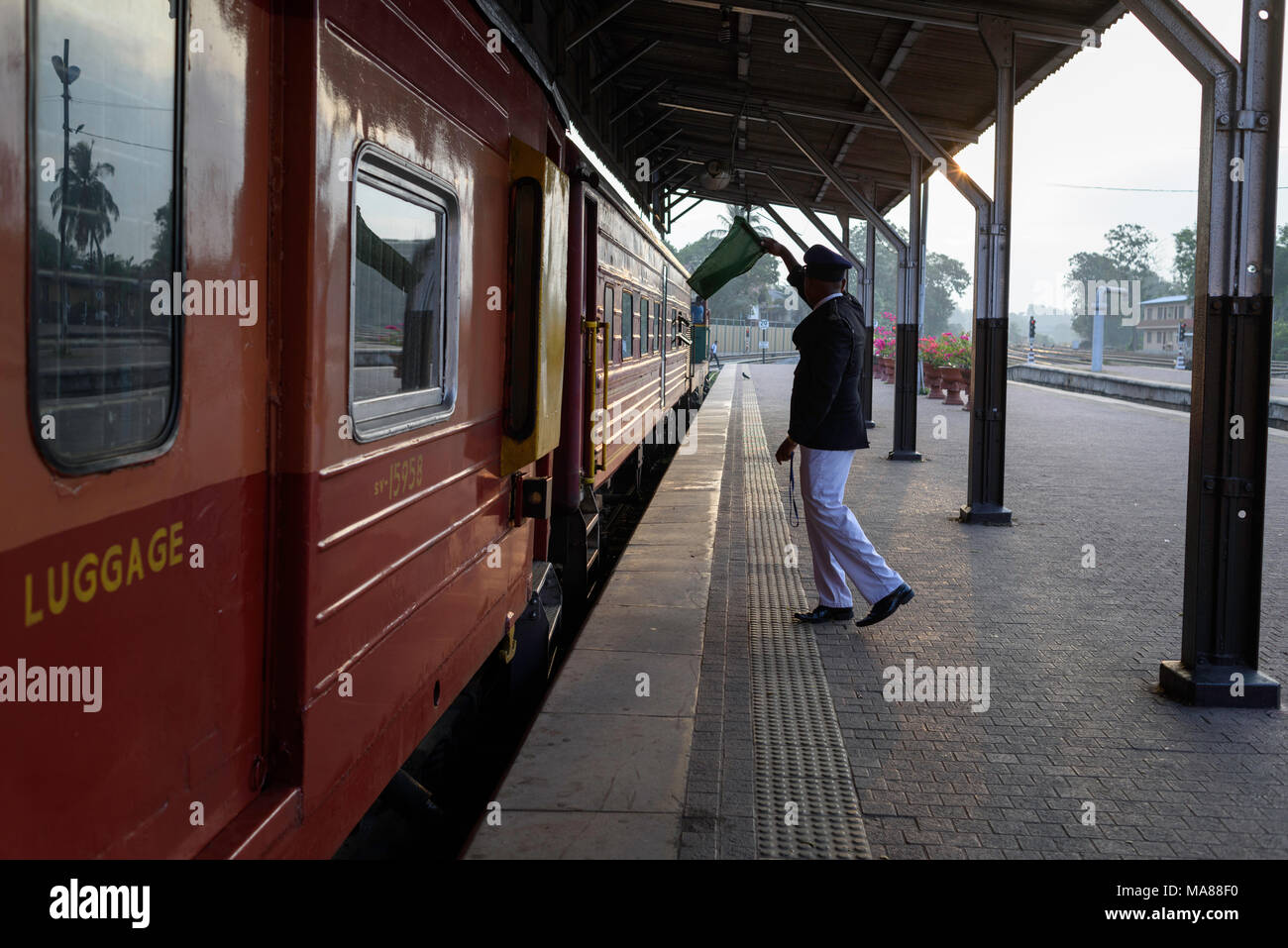 Il conduttore del treno dando il via con una bandiera verde a colombo fort stazione ferroviaria. Foto Stock