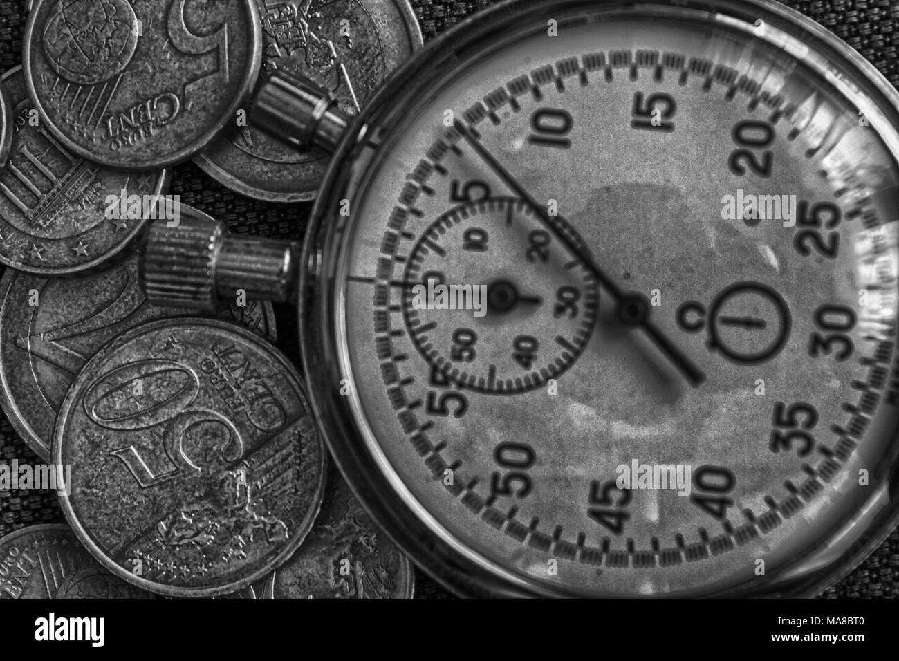 Pila di monete in euro con il vecchio vintage cronometro sul background del denim. Foto Stock