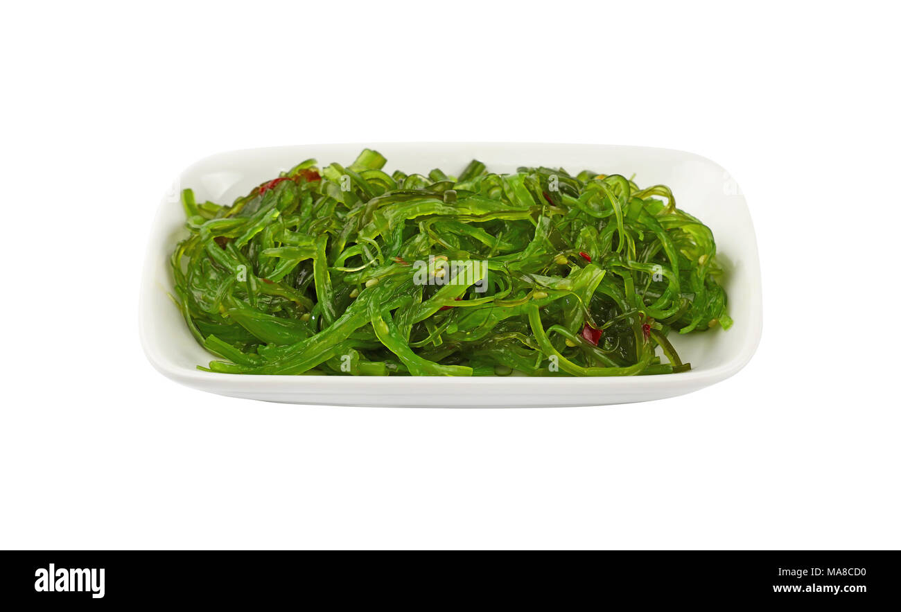 Vicino la porzione di verde alghe wakame salad sulla piastra bianca isolata su uno sfondo bianco, ad alto angolo di visione Foto Stock