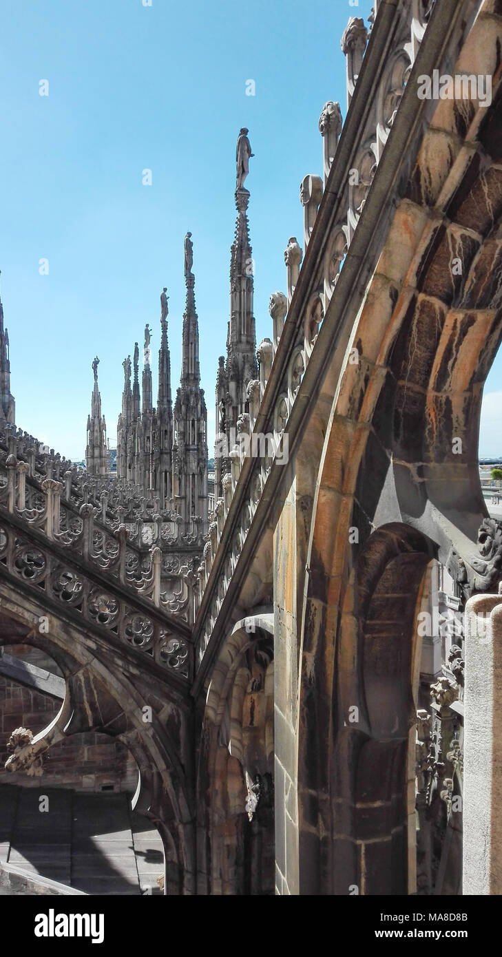 Alcuni spiers sormontata da statue del Duomo di Milano con un chiaro e blu cielo Foto Stock