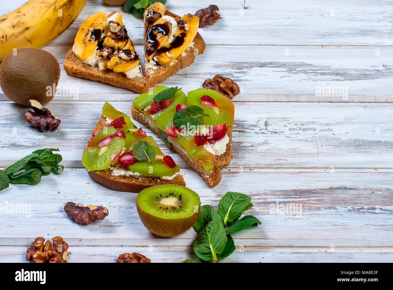 Sana colazione con pane tostato. Panini dolci con crema di formaggio e frutti di bosco freschi e frutta su sfondo bianco. Alimentazione sana Dieta e concetto. A Foto Stock