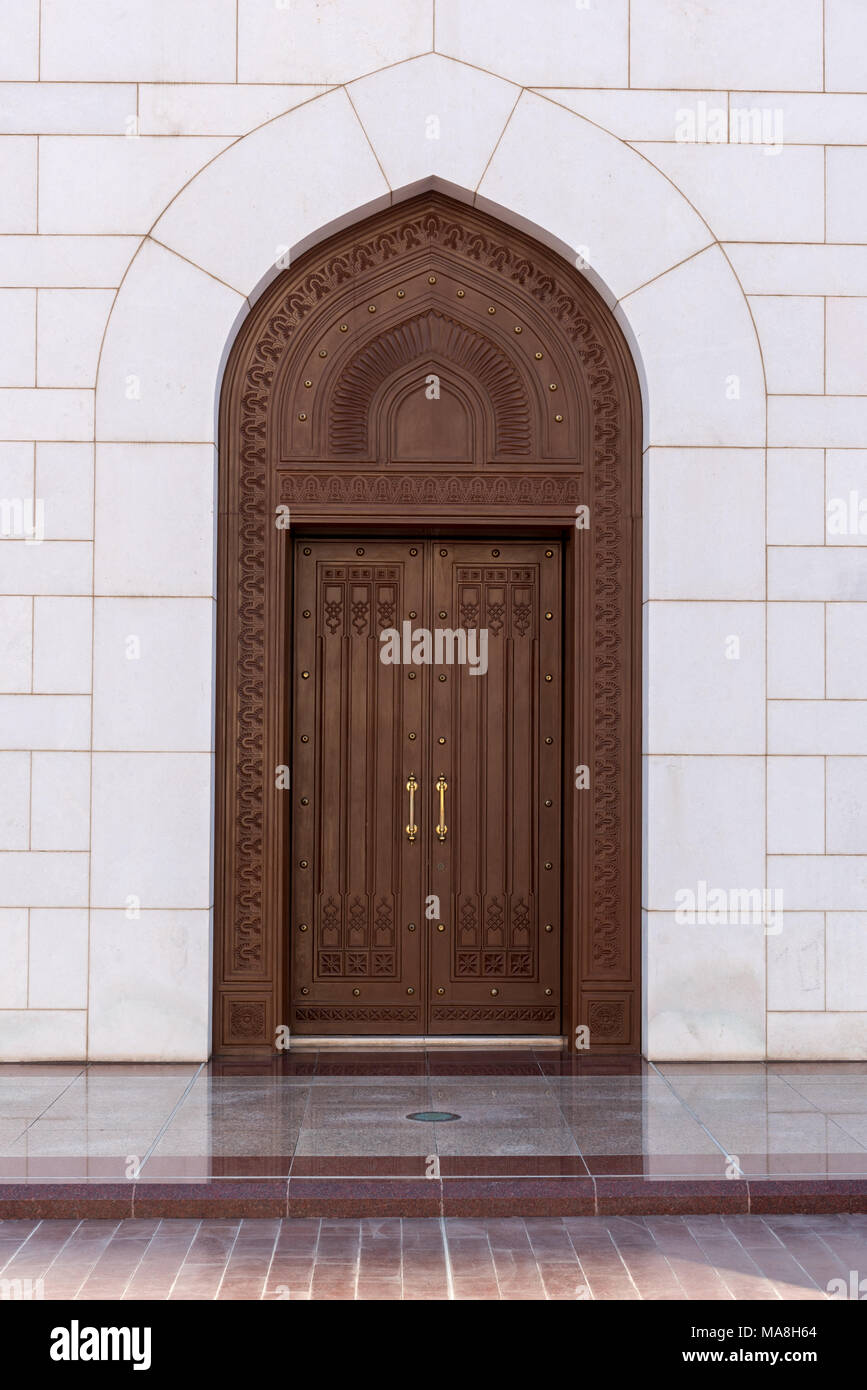 Un nuovo grande-cercando legno scuro porta con cerniere in ottone e perni sull'esterno di un edificio qhite in Muscat Oman Foto Stock