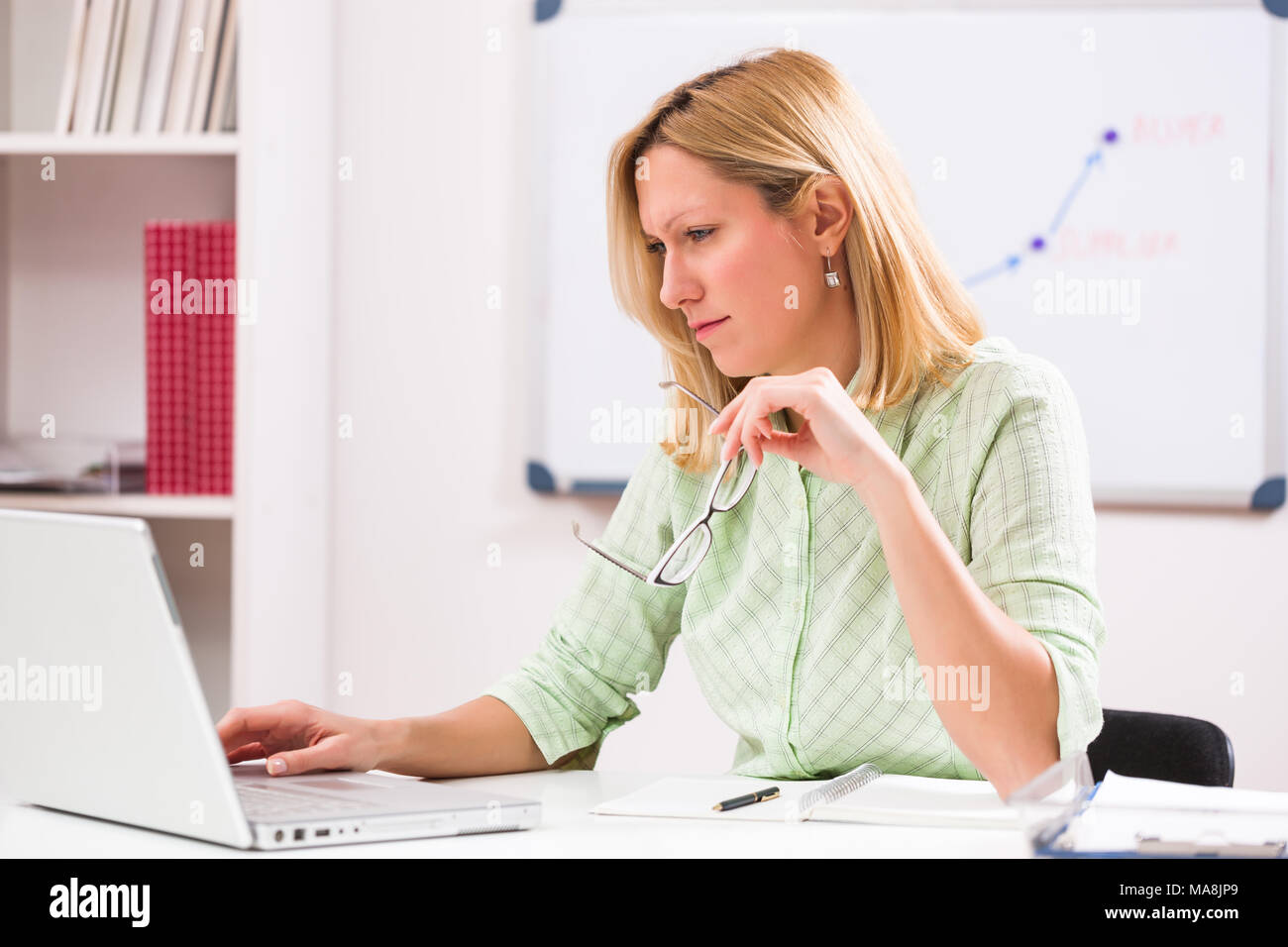 Imprenditrice sta lavorando sul computer portatile nel suo ufficio. Foto Stock