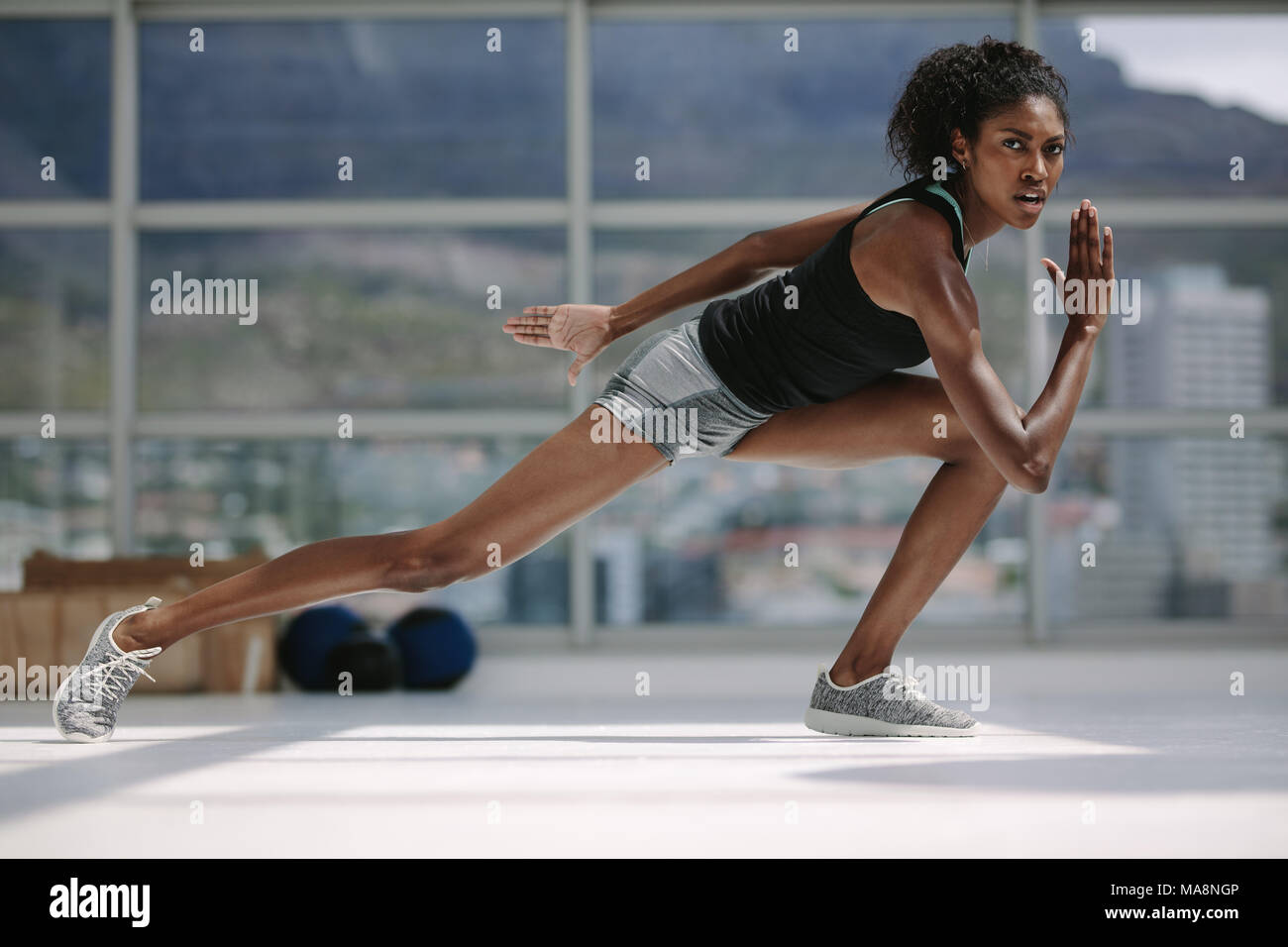 Donna africana con corpo sottile che si esercita in palestra. fitness femminile durante una sessione di allenamento fisico centro benessere. Foto Stock