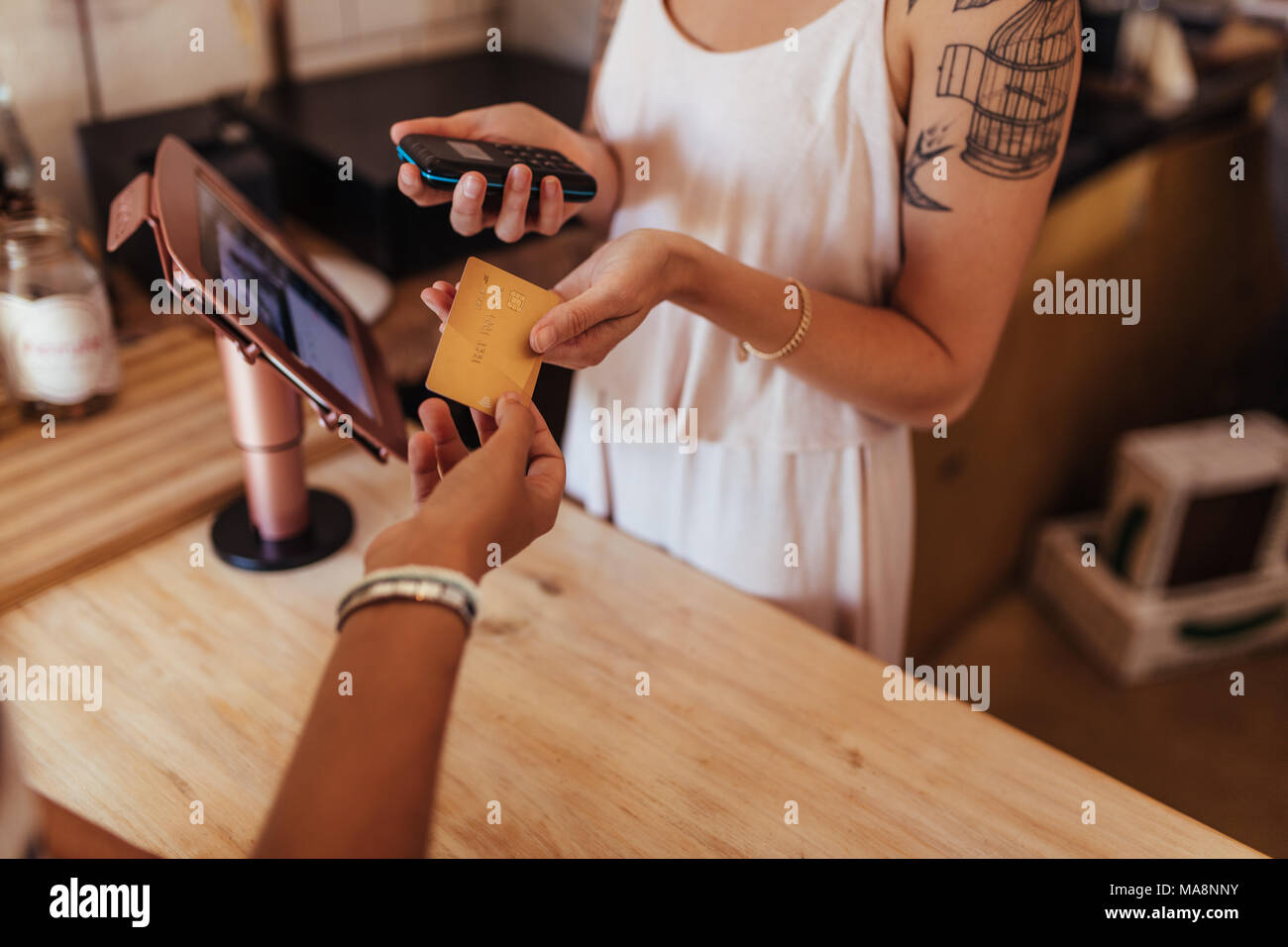 Il cliente pagare il conto utilizzando una carta di credito in un bar. Donna imprenditore tenendo un punto wireless di vendita macchina per effetto di transazione di carta. Foto Stock