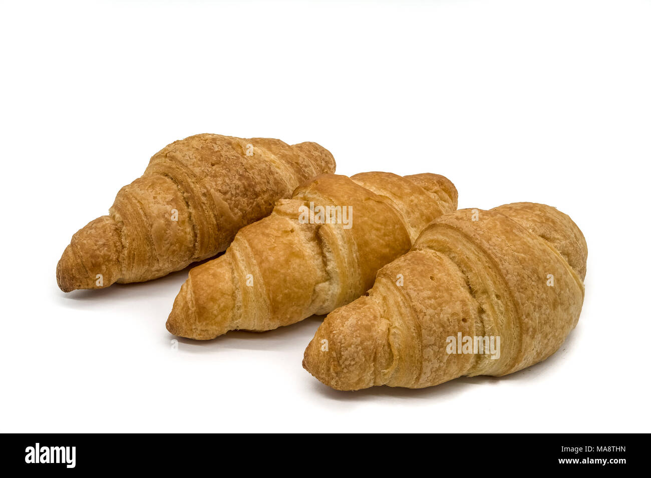 Tre croccanti croissant marrone su sfondo bianco affiancati Foto Stock
