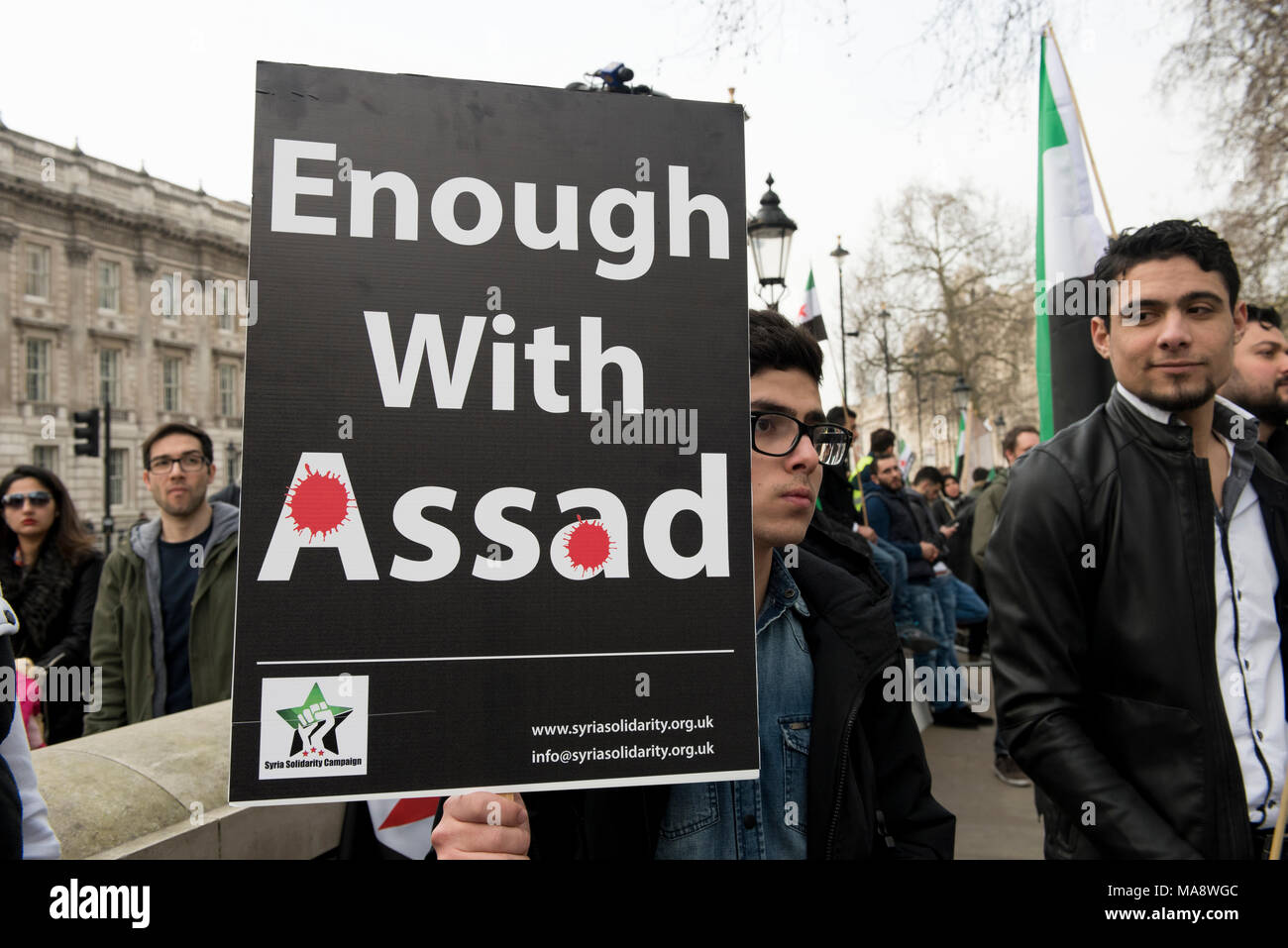 Un giovane manifestante siriano è in possesso di un cartellone di lettura: "Basta con Assad" al di fuori di Downing Street a Londra, Regno Unito. Foto Stock