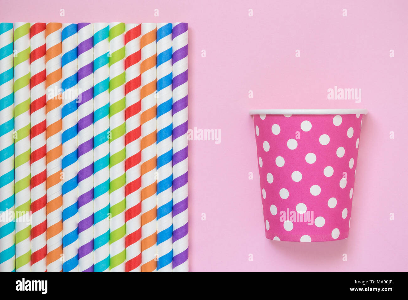 A strisce colorate di bere cannucce e bicchiere di carta polka design sul rosa pastello minima di sfondo concetto creativo. Spazio per la copia. Foto Stock