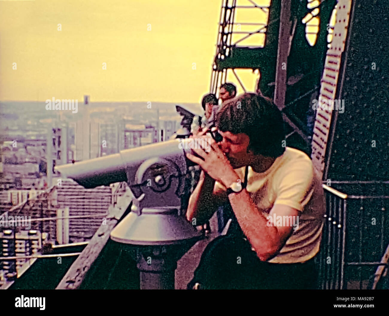 Parigi, Francia - circa 1976: Turisti in vintage 70s abito, guardando il panorama di Parigi dalla Torre Eiffel con il telescopio. Archivio Storico di riprese in Parigi città della Francia negli anni settanta. Foto Stock
