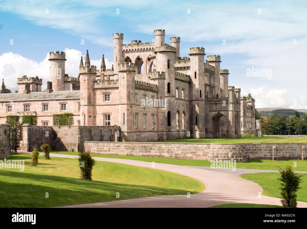 Lowther Castle, Lowther Park, Lake District, Cumbria, Inghilterra, Regno Unito. Castello inglese con vialetto in primo piano e il castello di sfondo. Cielo blu Foto Stock