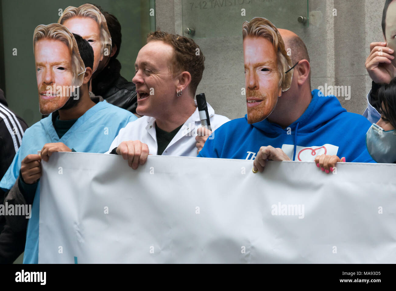 Manifestanti con Richard Branson maschere a cura di vergine HQ a Londra chiamata per porre fine alla società privata utilizzando il logo di NHS e per la Vergine a smettere di elusione fiscale. Foto Stock