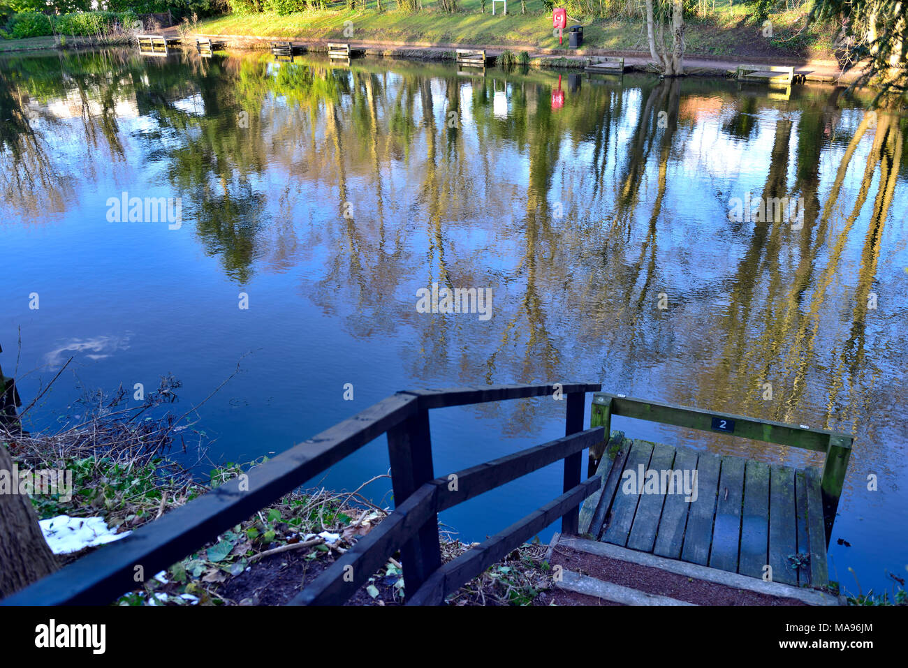 Riflessi di alberi in acqua ancora di Heriotts Piscina con nuoto ponti accanto a Droitwich Spa Lido Foto Stock