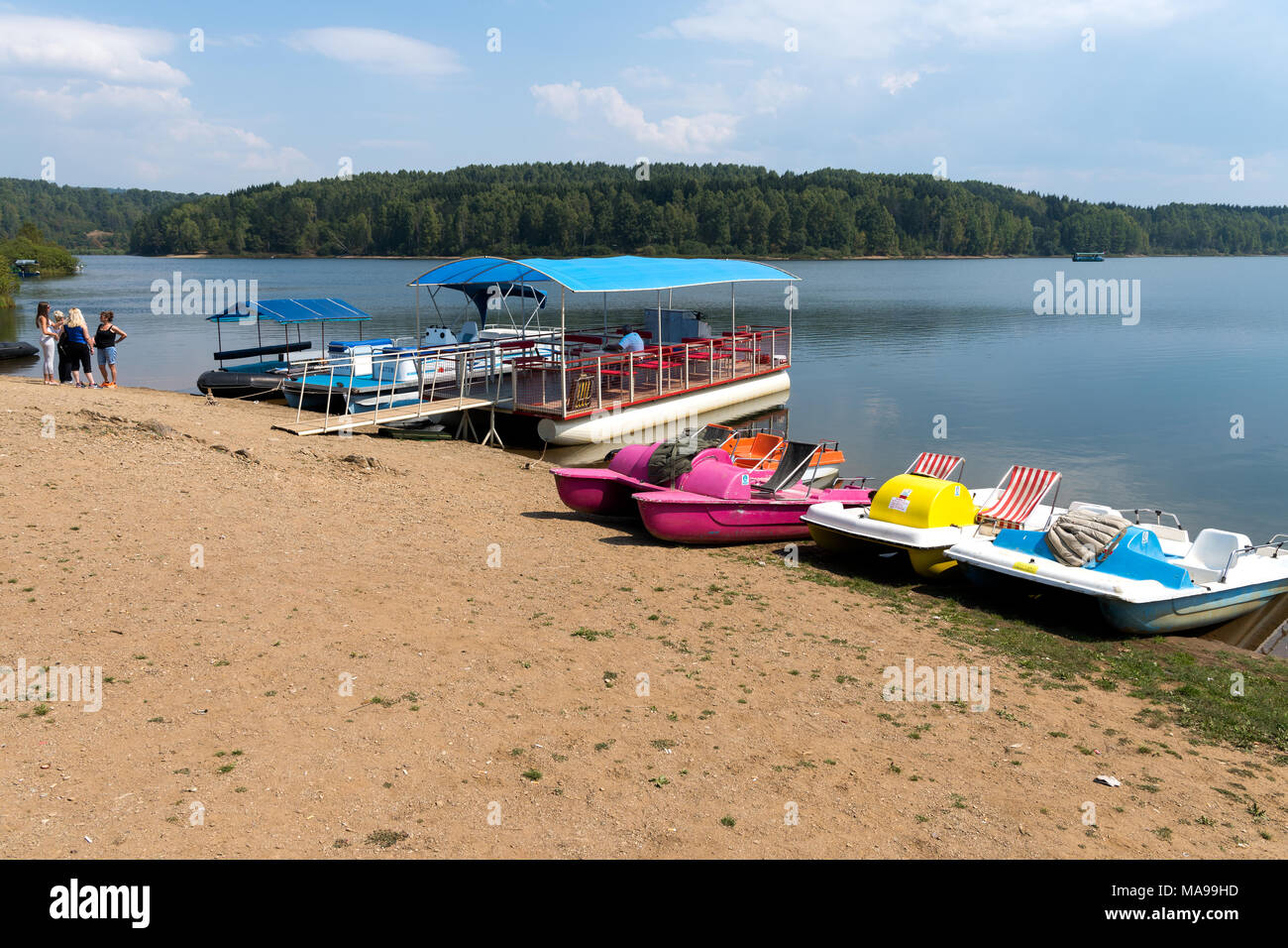 Vlasina lago, Serbia - 02 Settembre 2017: in plastica colorate barche a remi a noleggio e grandi imbarcazioni turistiche sulla riva del lago Vlasina, Serbia con s Foto Stock