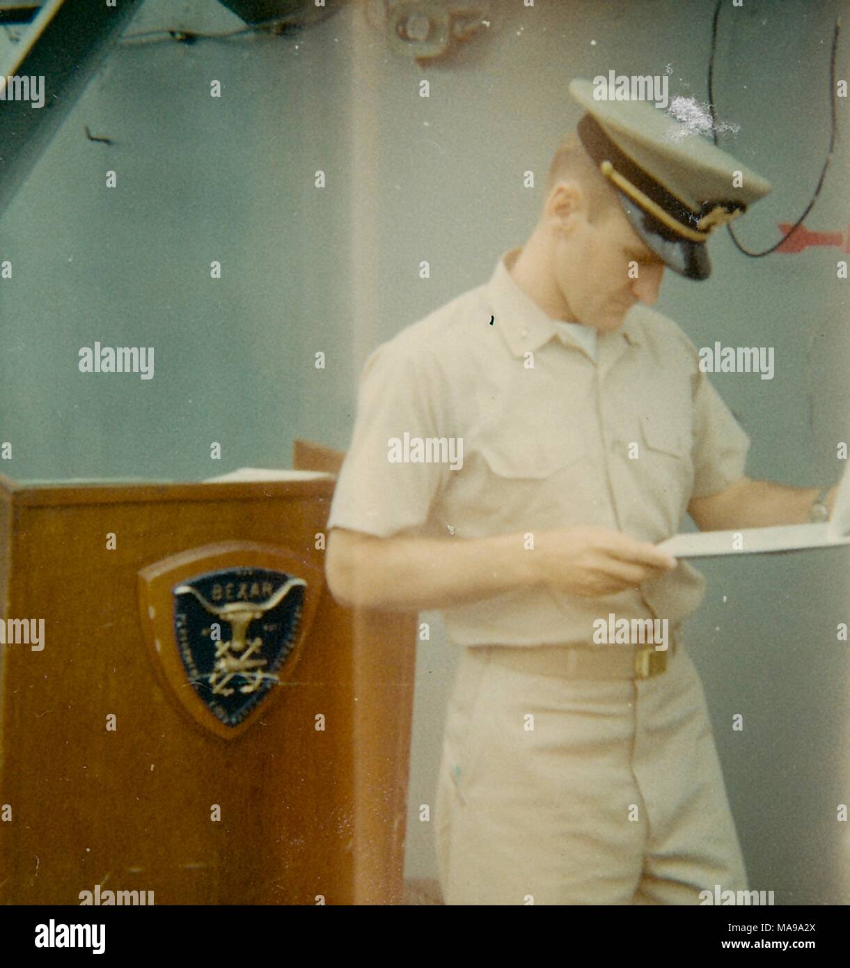 Fotografia a colori, di un soldato di sesso maschile, in piedi accanto a un podio, mostrato in tre quarti di vista di profilo, che indossa una uniforme e hat e guardando le carte su una clipboard con un espressione seria sul suo volto, fotografato in Vietnam durante la Guerra del Vietnam, 1968. () Foto Stock