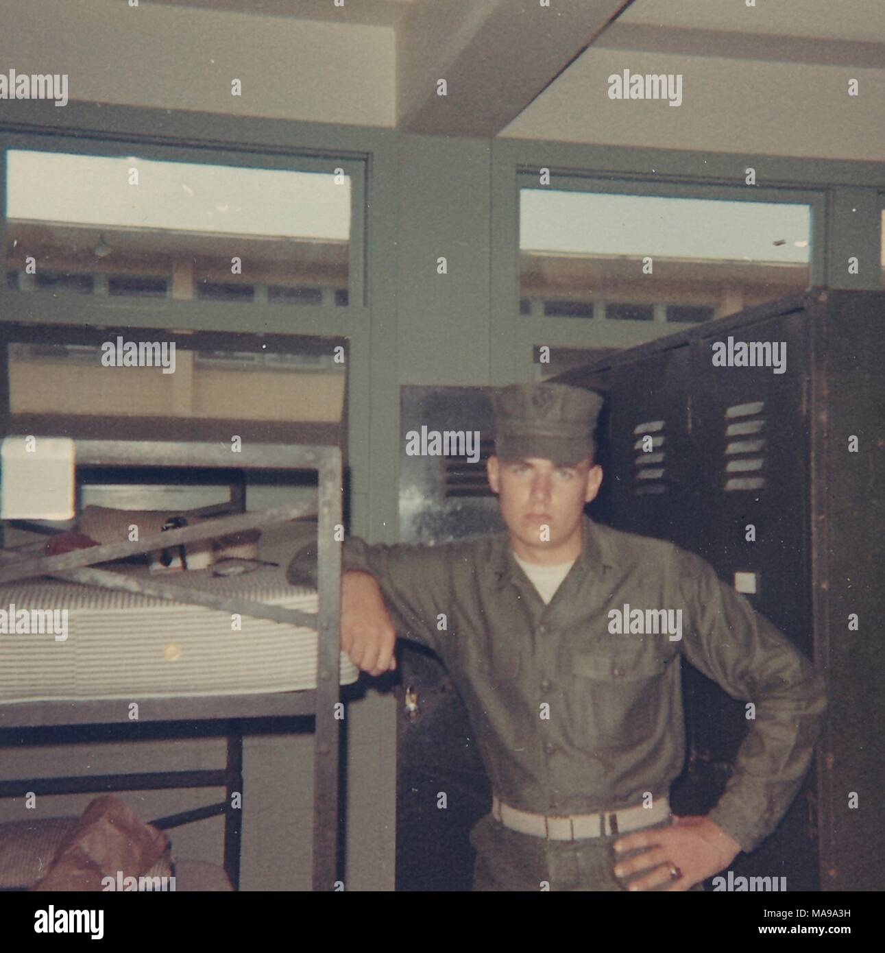 Fotografia a colori, di un maschio di Marine, mostrato in vista in tre quarti, che indossa una uniforme e hat e guardando la telecamera con un espressione seria sul suo volto, mentre appoggiato un braccio sul bordo di un top-level cot, presumibilmente girato all'interno di una caserma, fotografato in Vietnam durante la Guerra del Vietnam, 1968. () Foto Stock