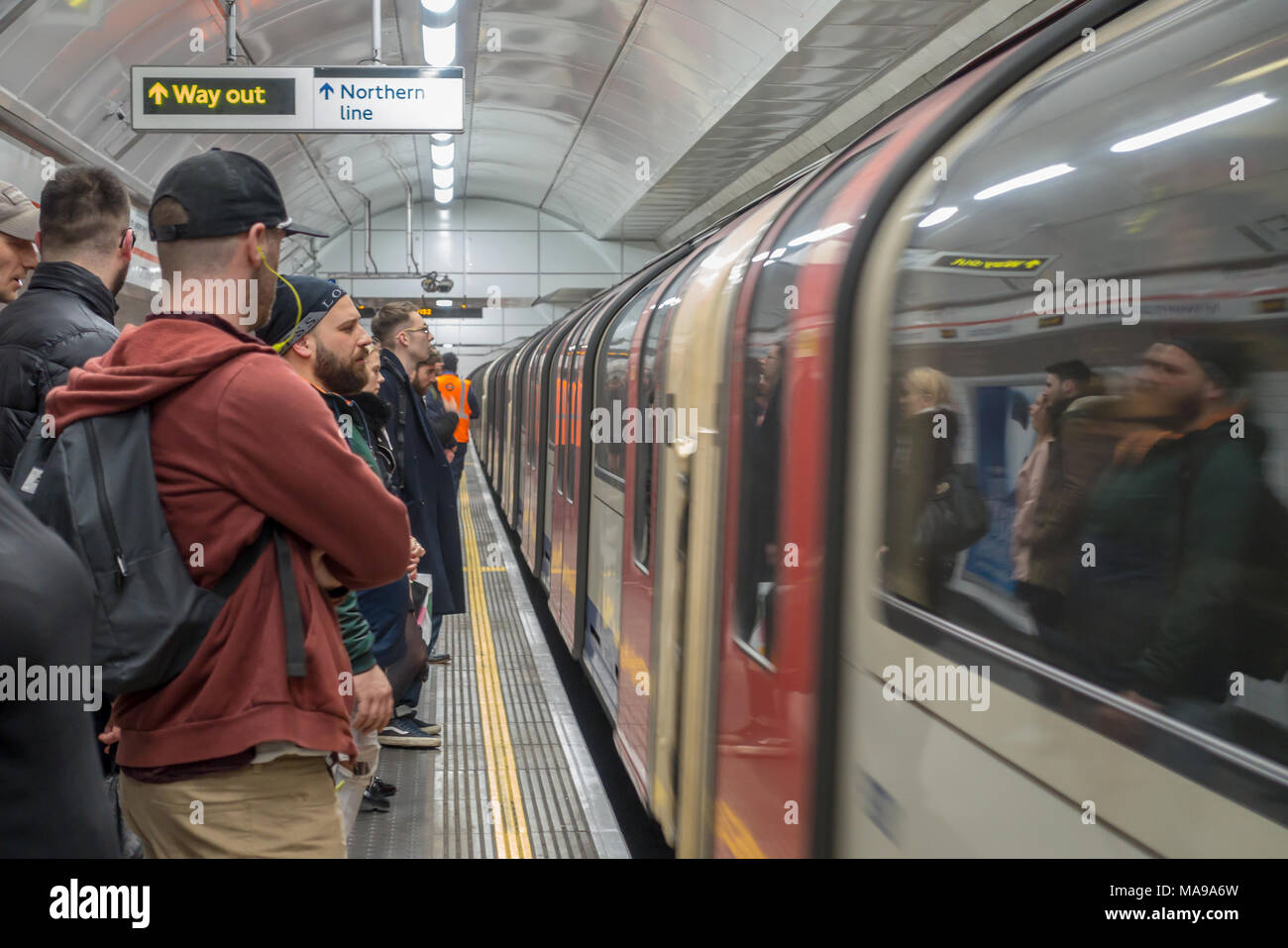 La gente in attesa di salire su un treno che è appena arrivato in corrispondenza di una stazione della metropolitana di Londra. Foto Stock