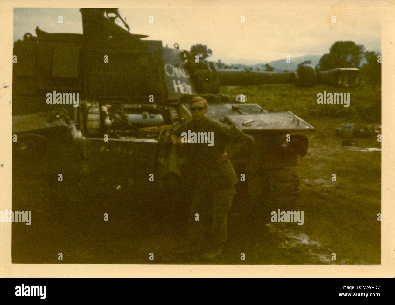 Fotografia a colori, di una bionda, maschio soldato, mostrato in full-length, vista in posa nella parte anteriore di un serbatoio, con un espressione seria sul suo volto, indossando una uniforme e occhiali da sole, fotografato in Vietnam durante la Guerra del Vietnam (1955-1975), 1971. () Foto Stock