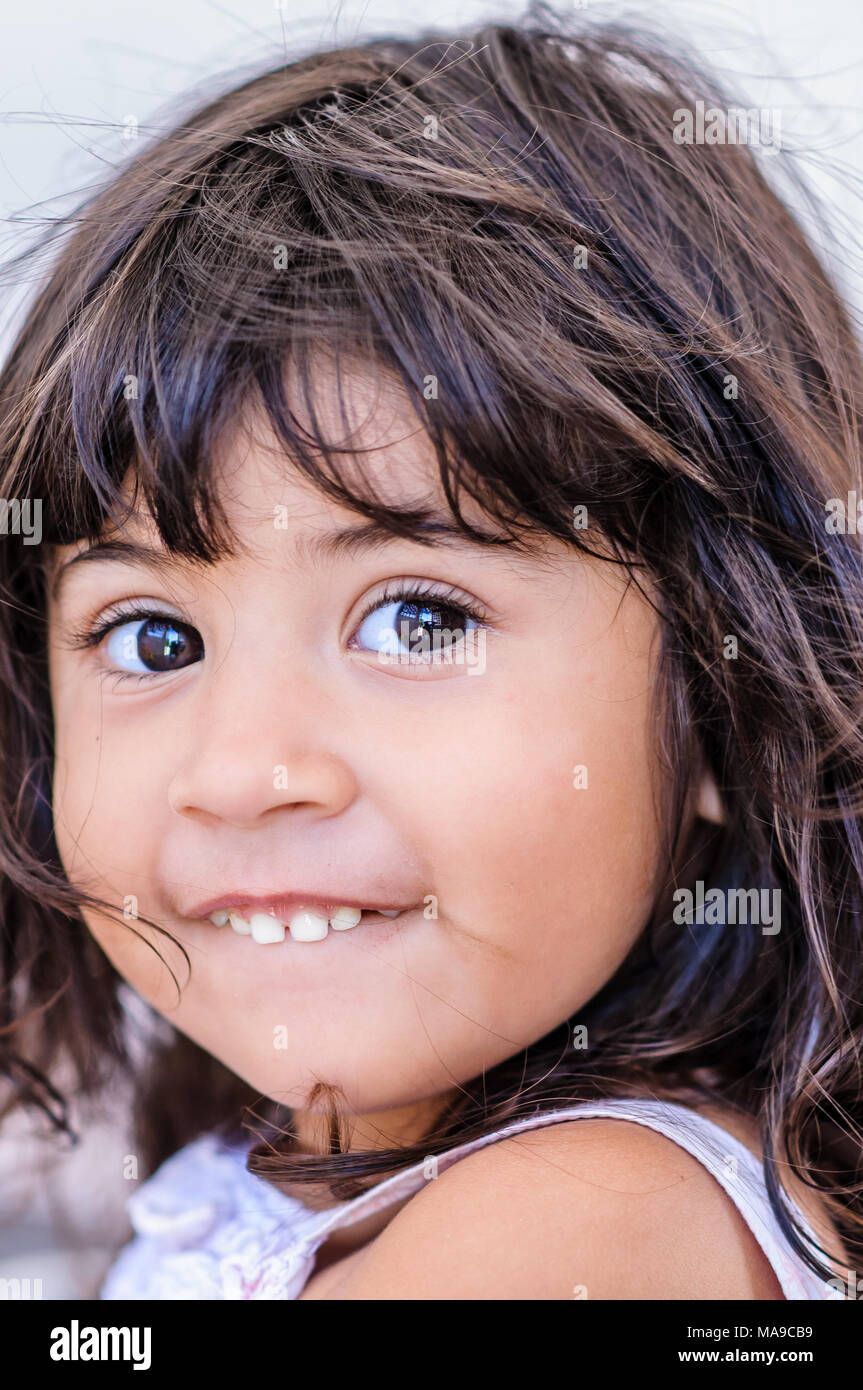 Mexican bambina a scuola sorridente con sguardo furtivo e denti fuori Foto Stock