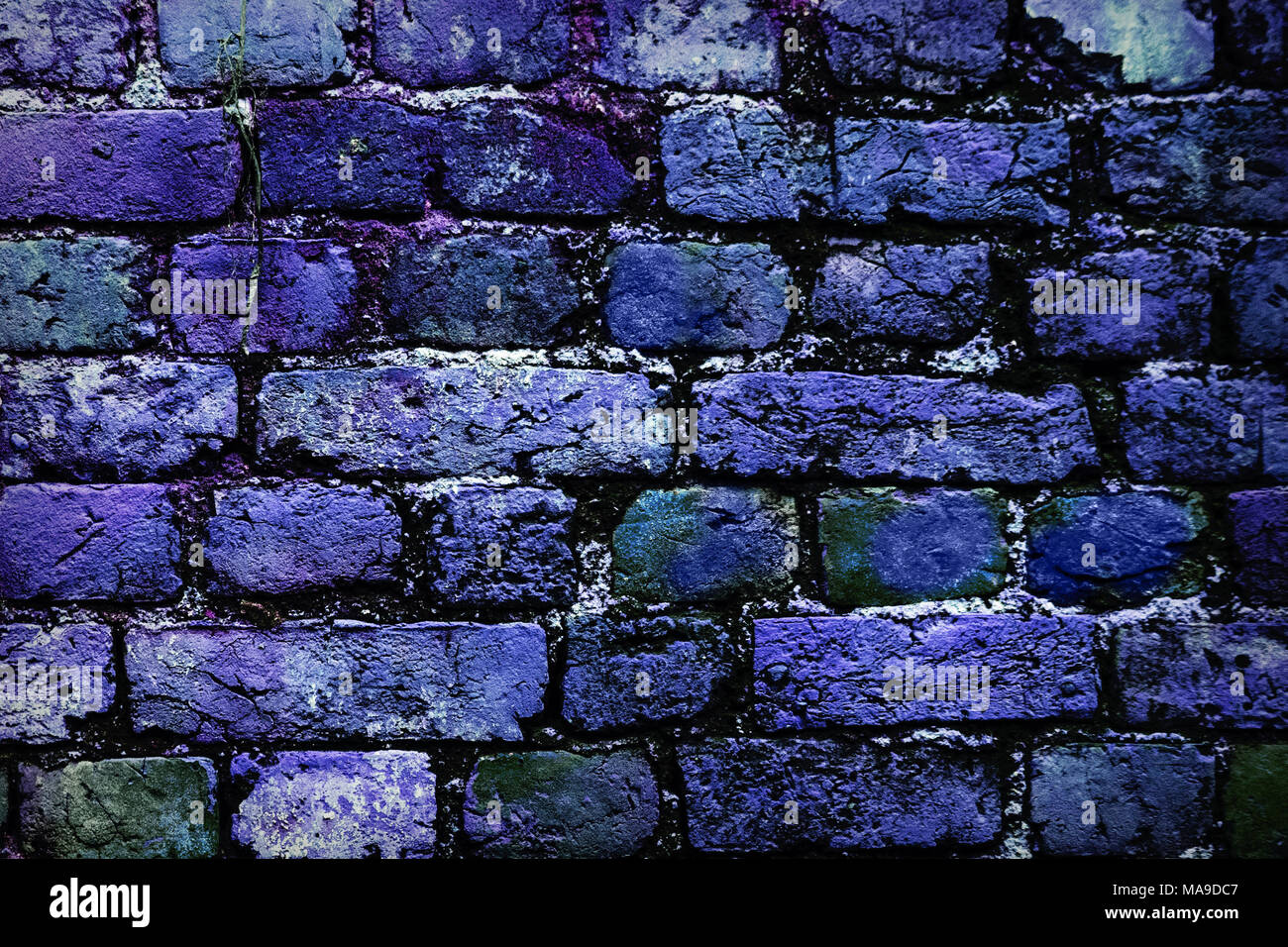 Il profondo blu del muro di mattoni sfondo sbiadito su nero. Muro di mattoni dipinto in colori luminosi. Mattoni di colore blu nella parete. Foto Stock