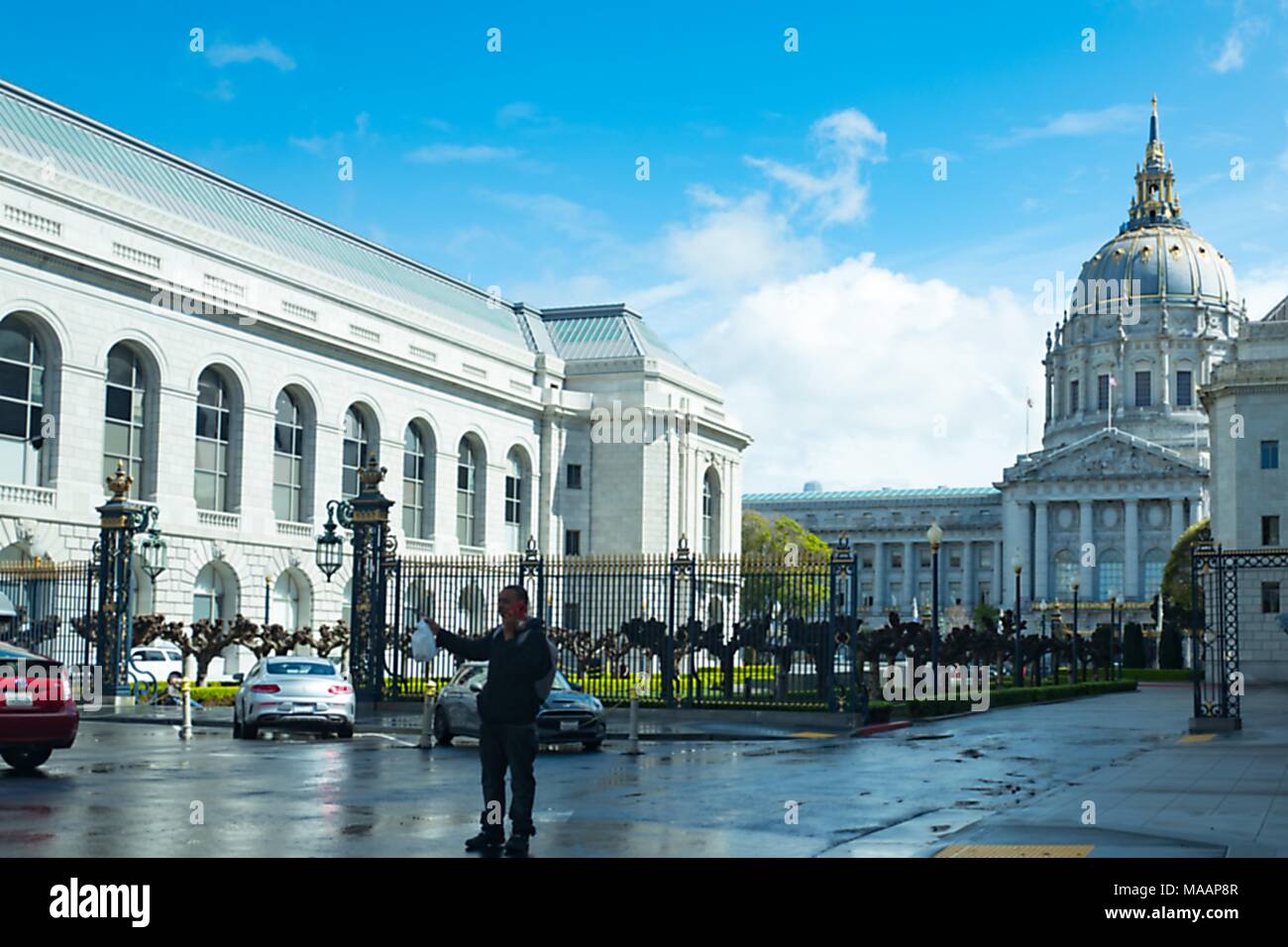 Un uomo che si trova in primo piano nella parte anteriore della cupola ornata di San Francisco City Hall nel Centro Civico quartiere di San Francisco, California, 14 marzo 2018. () Foto Stock
