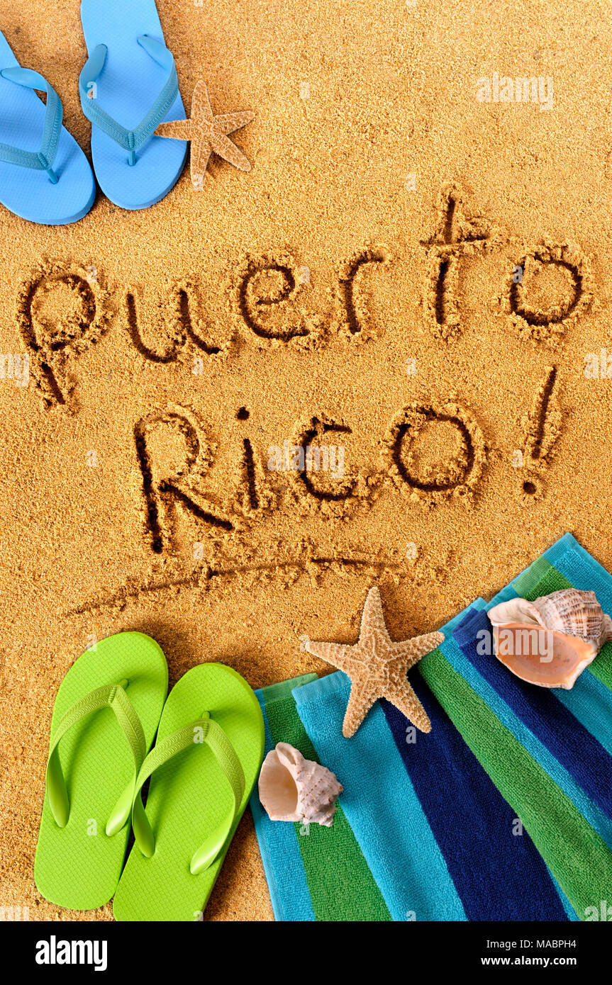 Le parole di Puerto Rico scritto su di una spiaggia di sabbia con telo mare, stelle marine e flip flop. Foto Stock