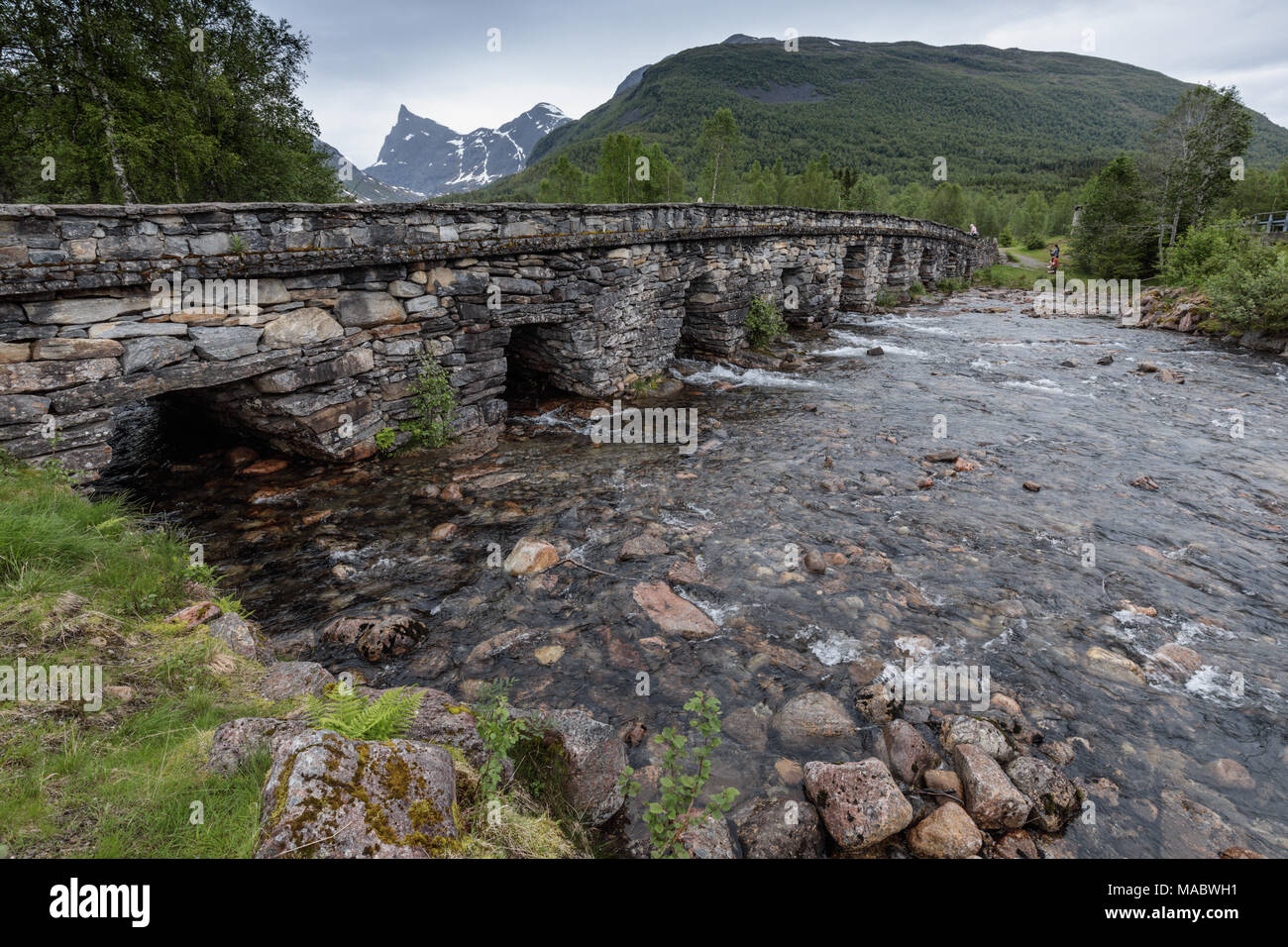 Il vecchio ponte di pietra costruito Honndøla 1810, vicino a Hellesylt, Norvegia. La montagna nella distanza è Hornindalsrokken che raggiunge i 5016 metri. Foto Stock