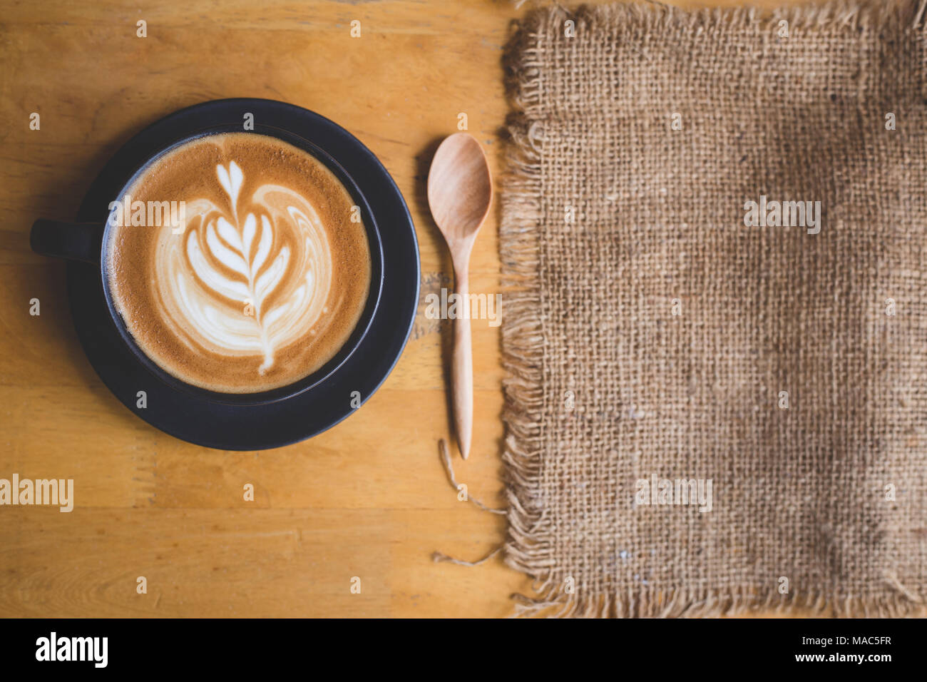 Una tazza di latte art sul chicco di caffè lo sfondo con il sacco per spazio di copia Foto Stock