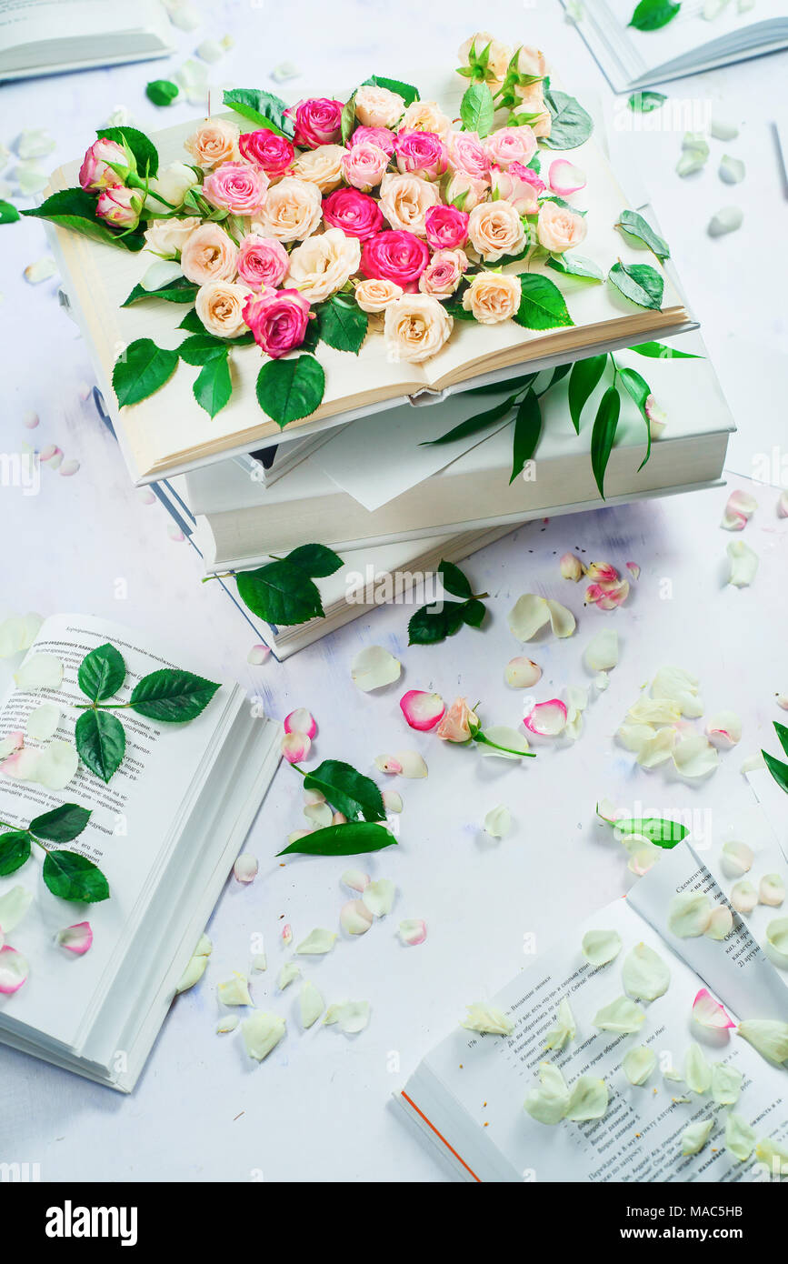Molla di concetto di lettura. Pila di libri bianchi con fiori e petali di fiori. Femminile di vita ancora in alta chiave con copia spazio. Foto Stock