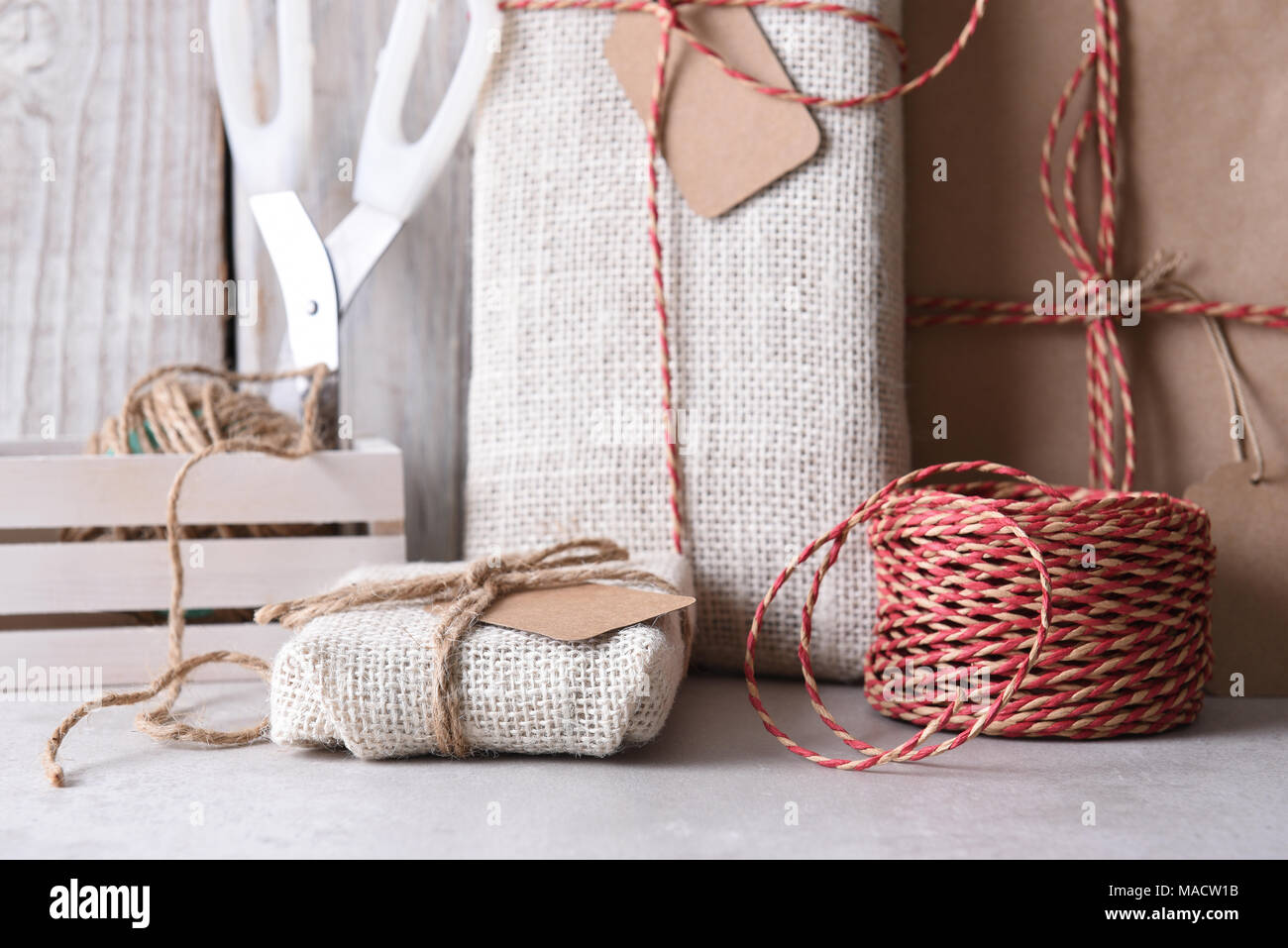 Impacchettare i regali di Natale. Vista dettagliata del tessuto e carta comune avvolto doni e strumenti di incarto ans forniture. Foto Stock
