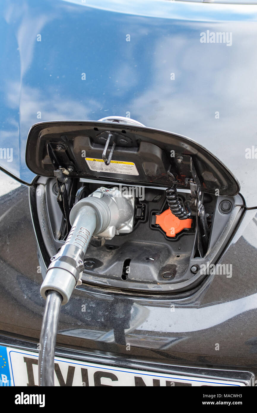 Un auto elettrica su carica in corrispondenza di un high street caricabatterie o punto di carica per ri-eccitare le batterie su questo futuro di una forma di trasporto. automobilismo moderno Foto Stock