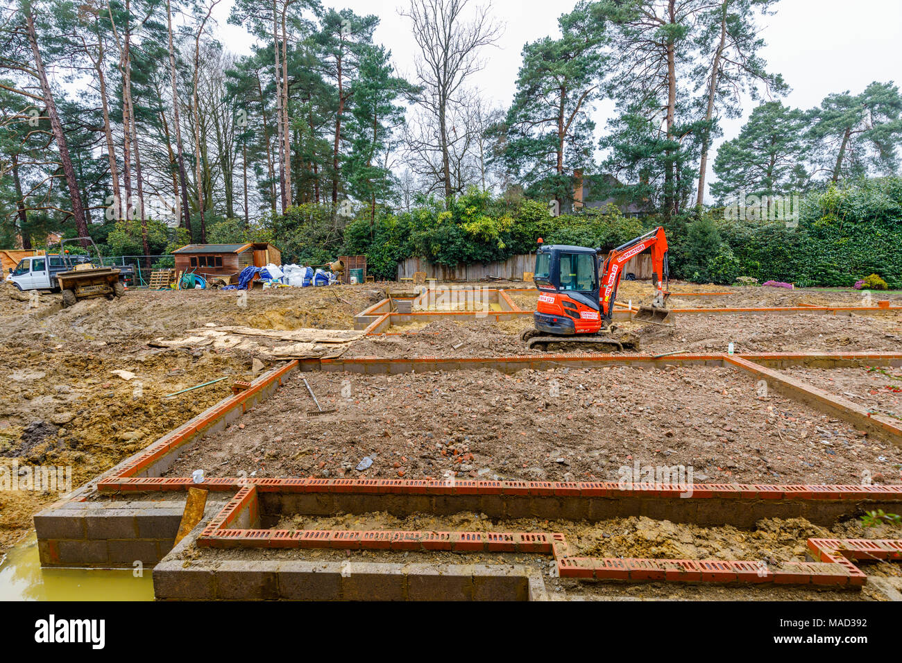 Orange Hitachi impianto pesante escavatore meccanico per le fondamenta di una nuova casa in costruzione su un edificio sito nel Surrey, Inghilterra sudorientale, REGNO UNITO Foto Stock