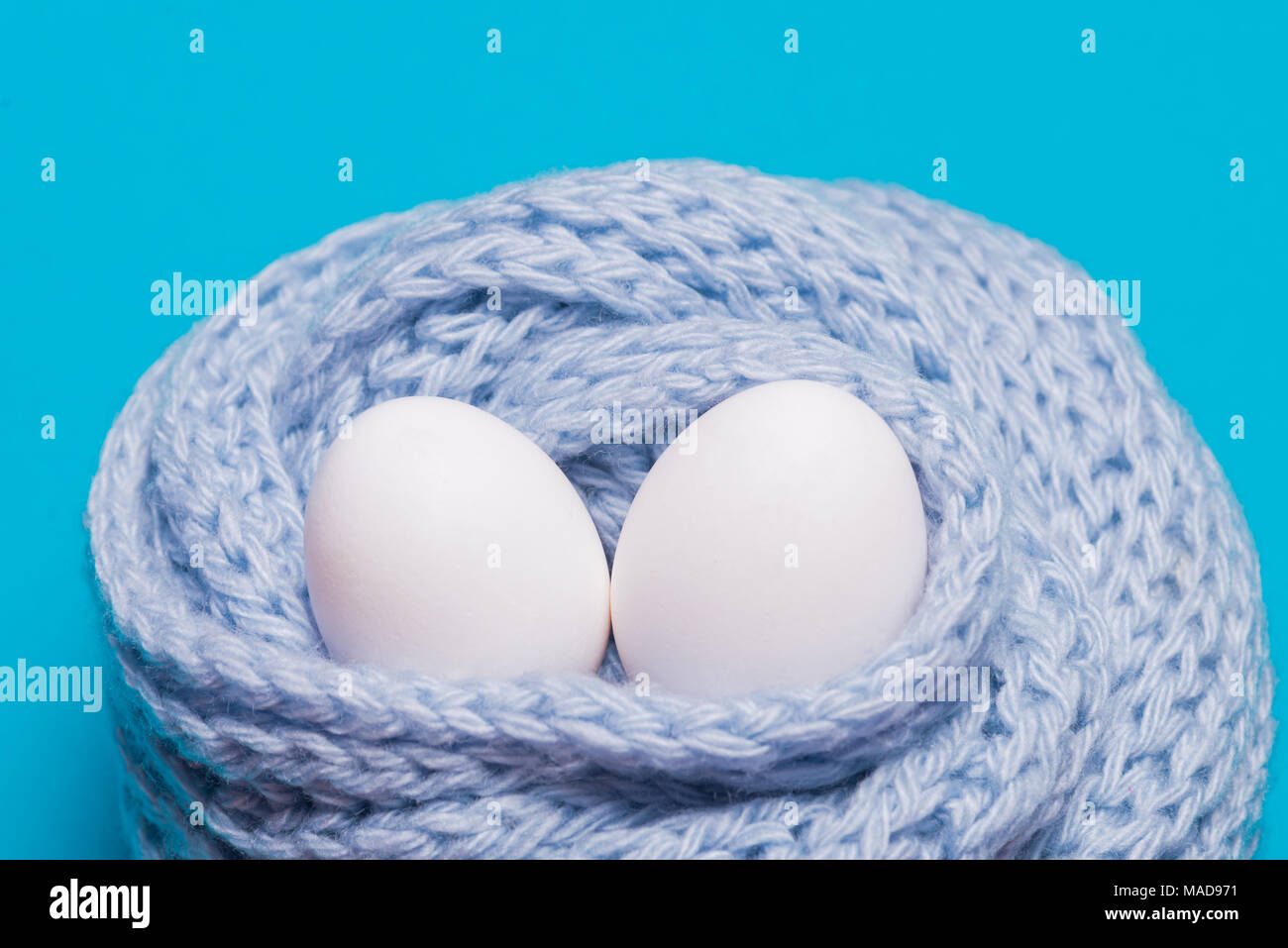 Due le uova bianche avvolto in una sciarpa lavorata a maglia Foto Stock