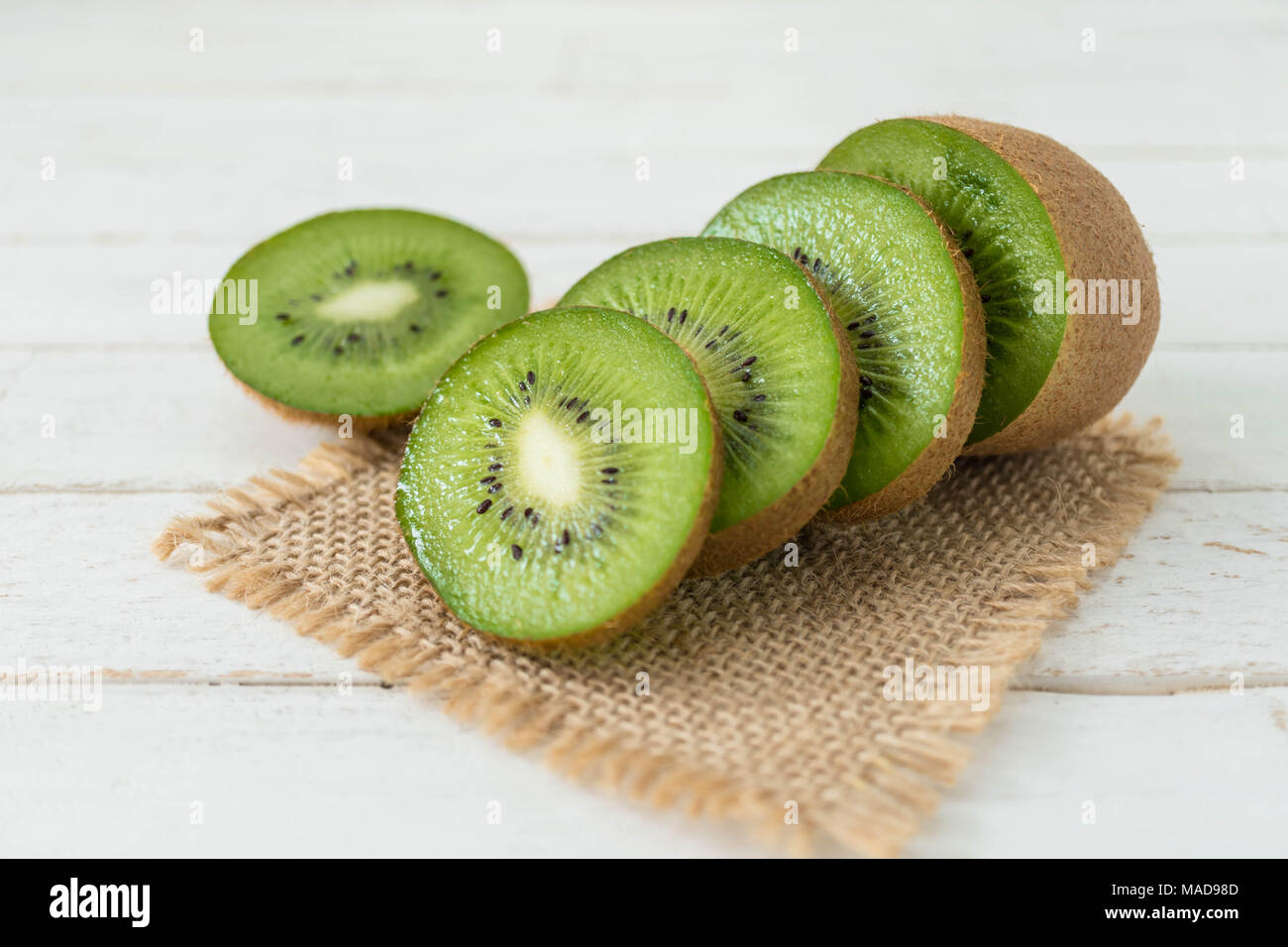 Fette di kiwi bianco su uno sfondo di legno con tela ruvida Foto Stock
