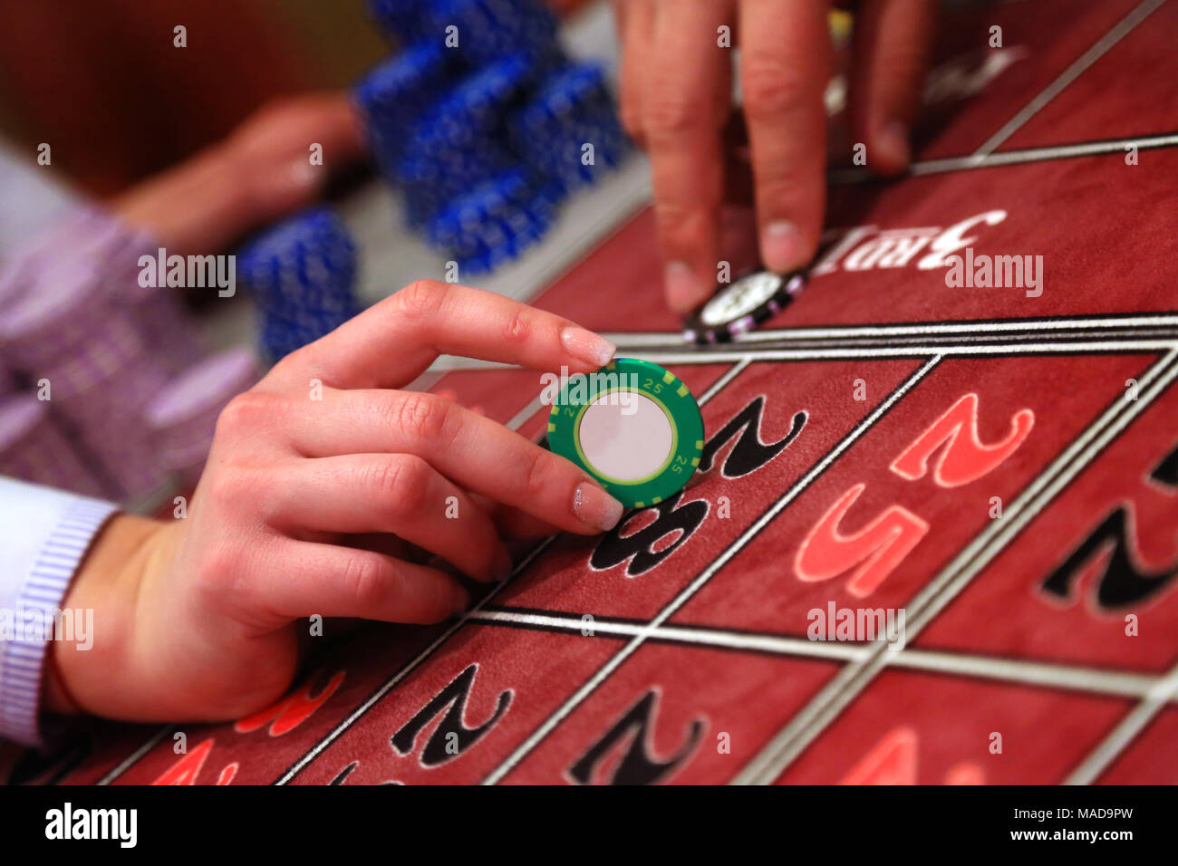 Casino giocatore in possesso di un chip verde, primo piano Foto Stock