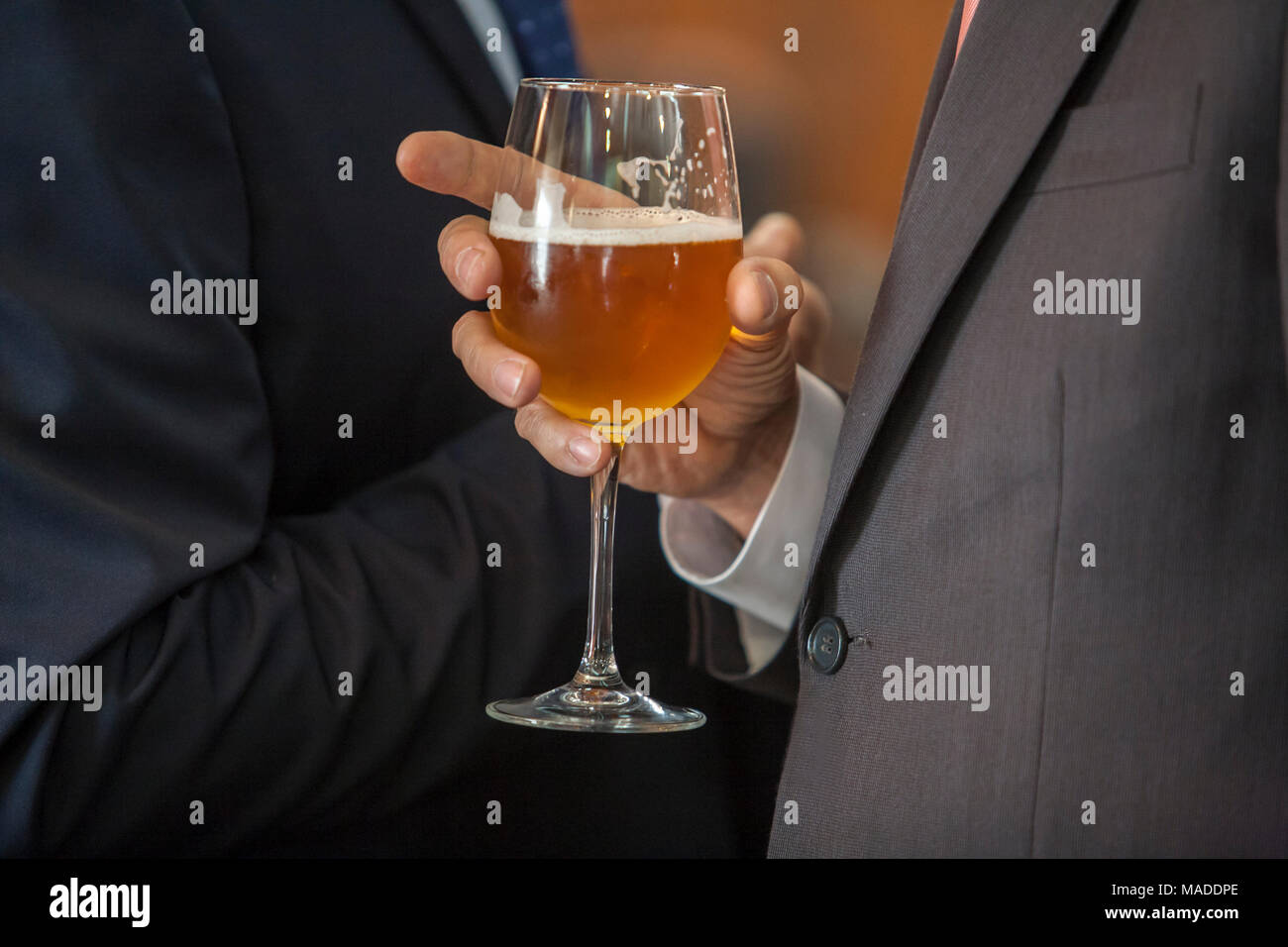 Le persone a bere birra al cocktail di benvenuto con abbigliamento formale. Due uomini con un calice di vetro. Messa a fuoco selettiva Foto Stock