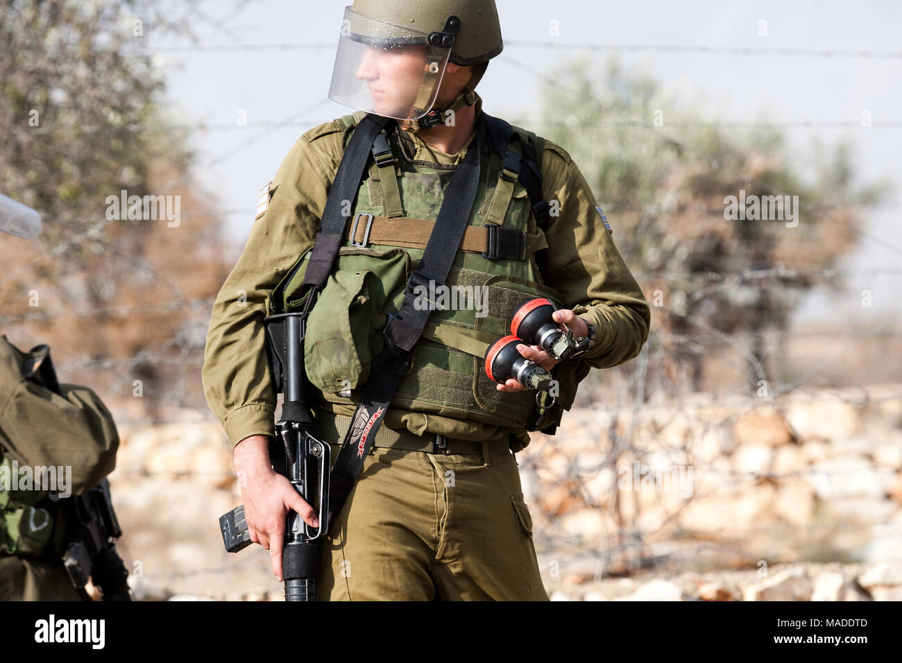 Bilin, Palestina, Dicembre 31, 2010: Israele Defense Force soldato è azienda le scatole metalliche del gas lacrimogeno durante manifestazioni settimanali contro il territorio palestinese Foto Stock