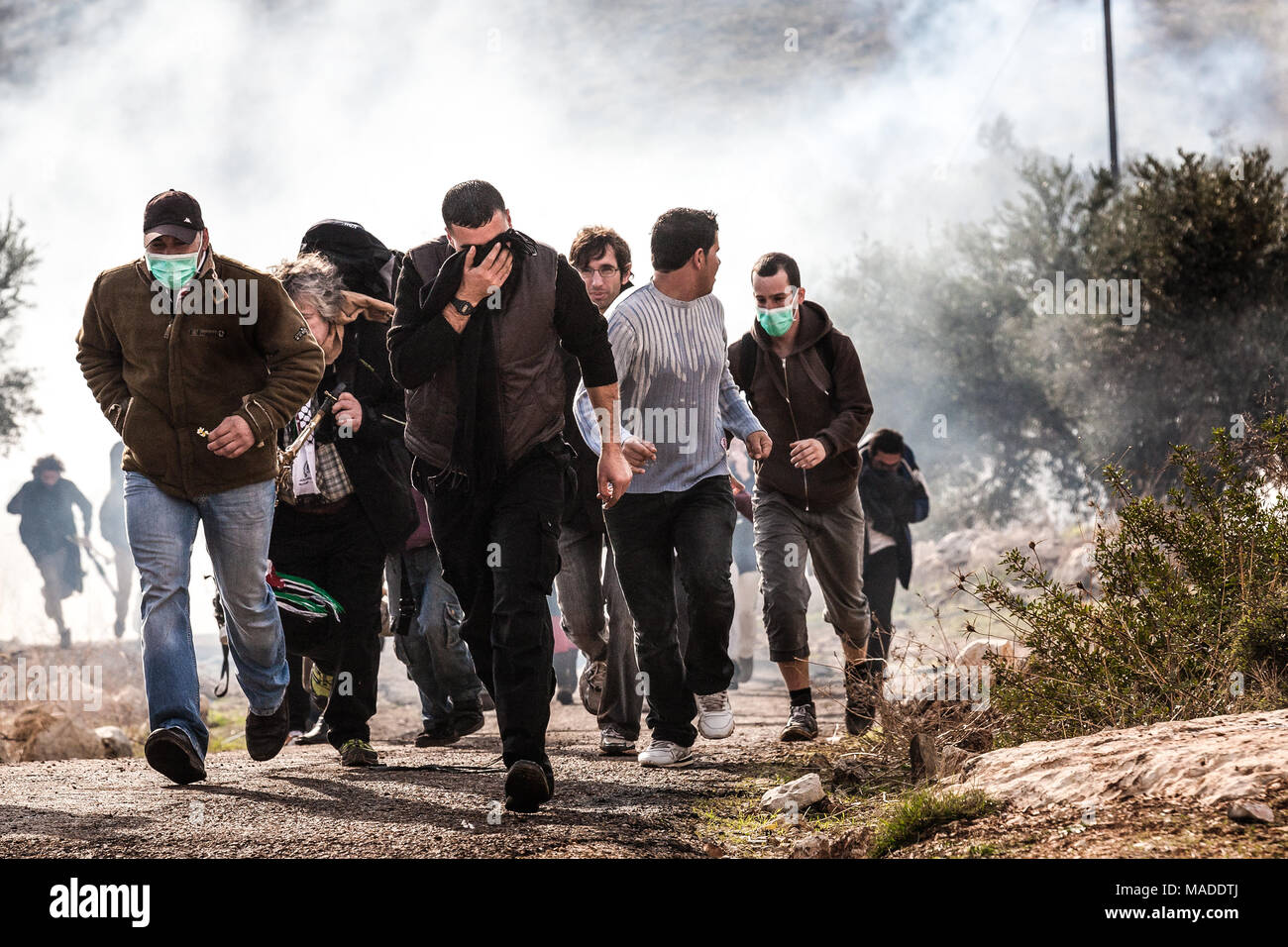 Bilin, Palestina, Dicembre 31, 2010: palestinese manifestanti sfuggire il gas lacrimogeni durante manifestazioni settimanali contro terra palestinese e di confisca Foto Stock
