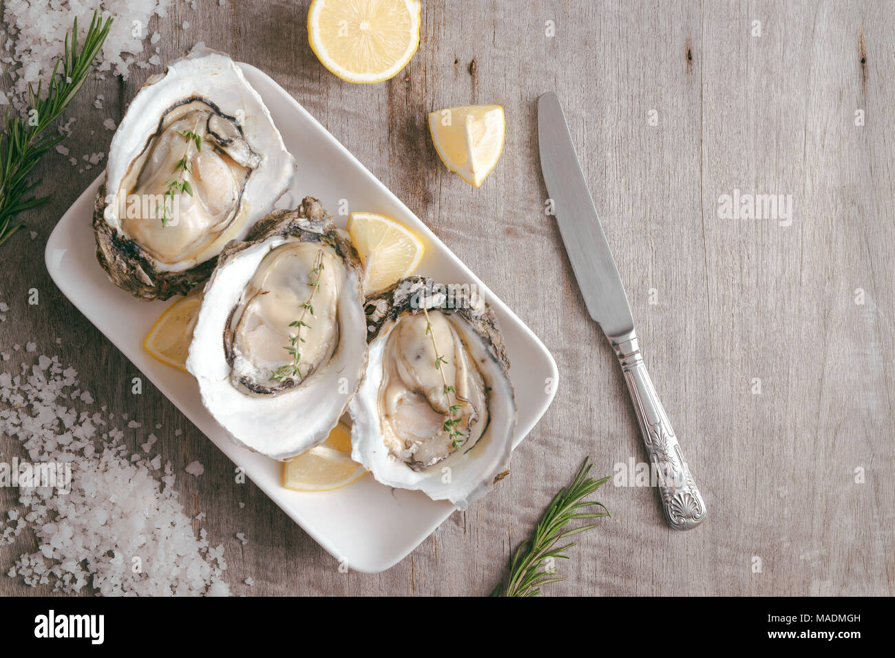 Aprire le ostriche, limone su grigio tavolo di pietra. Mezza dozzina. Con spazio di copia Foto Stock