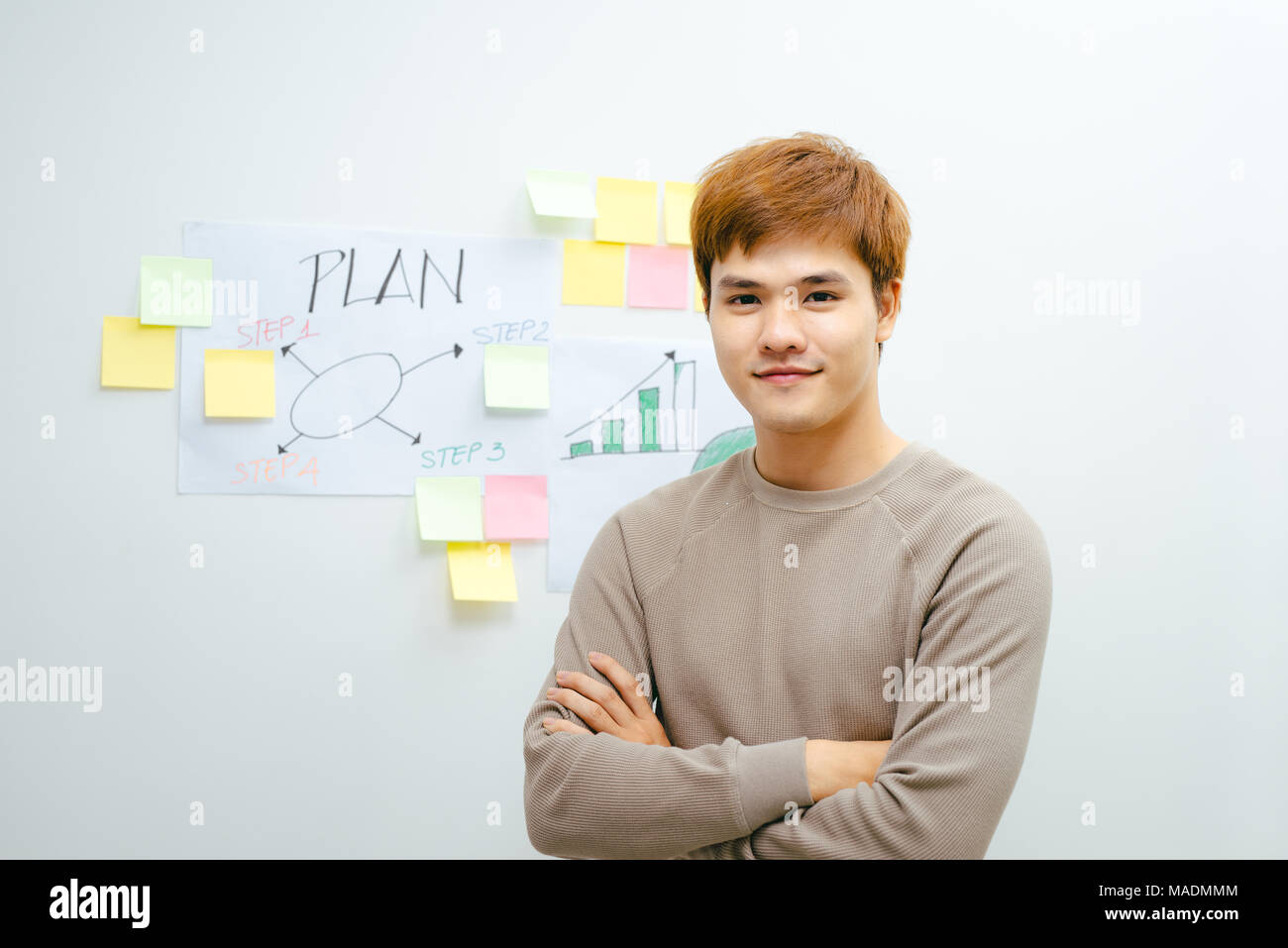 Giovane uomo asiatico si erge di fronte al suo piano finanziario in camera Foto Stock