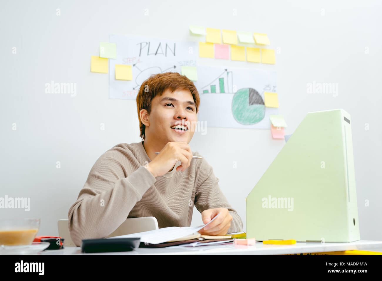 Giovane uomo asiatico seduto davanti al suo piano finanziario in camera Foto Stock