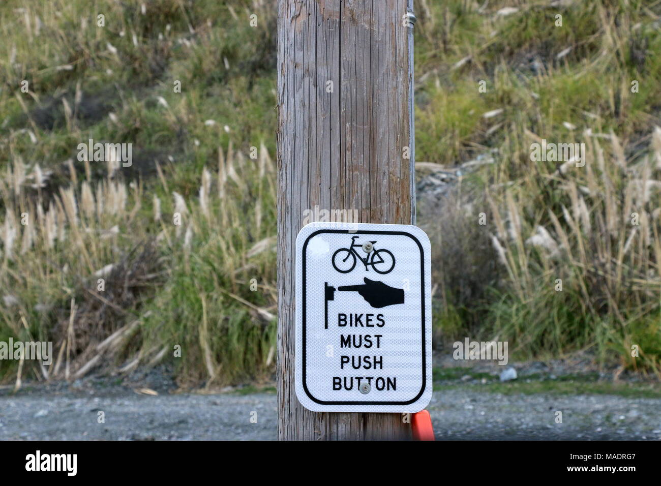 Spingere il pulsante di attraversamento stradale segno per i ciclisti. Foto Stock