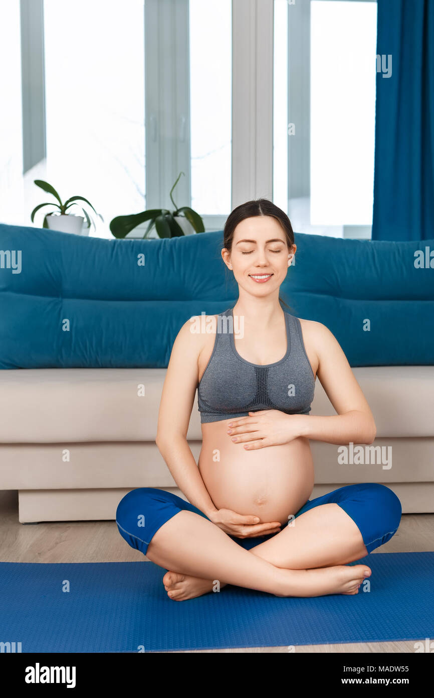Felice donna incinta facendo esercizi yoga a casa. Donna incinta medita. Gravidanza gravidanza, yoga, uno stile di vita sano concetto Foto Stock