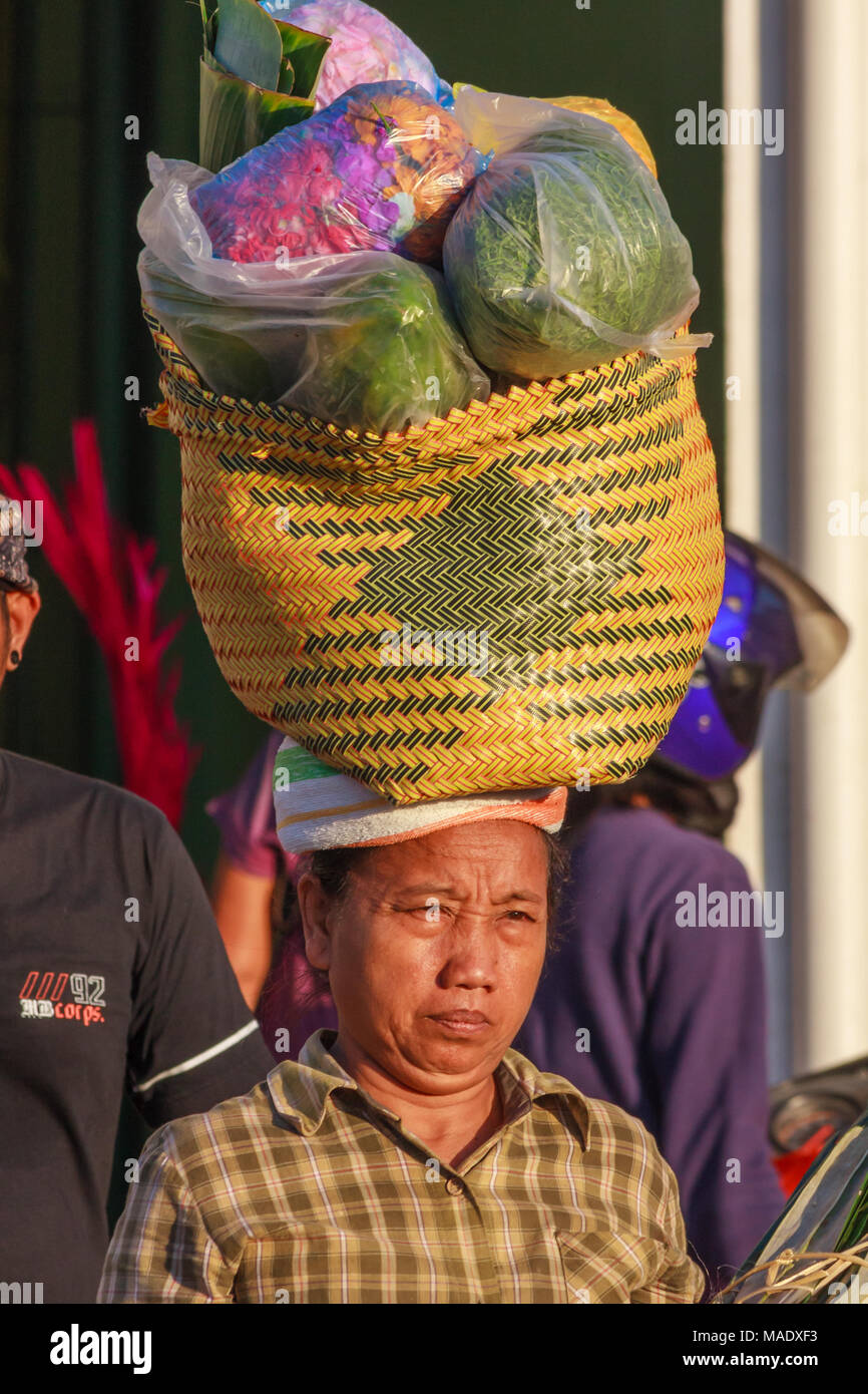 Donna Balinese lasciando portante del mercato cestino di shopping sul suo capo, Bali, Indonesia Foto Stock