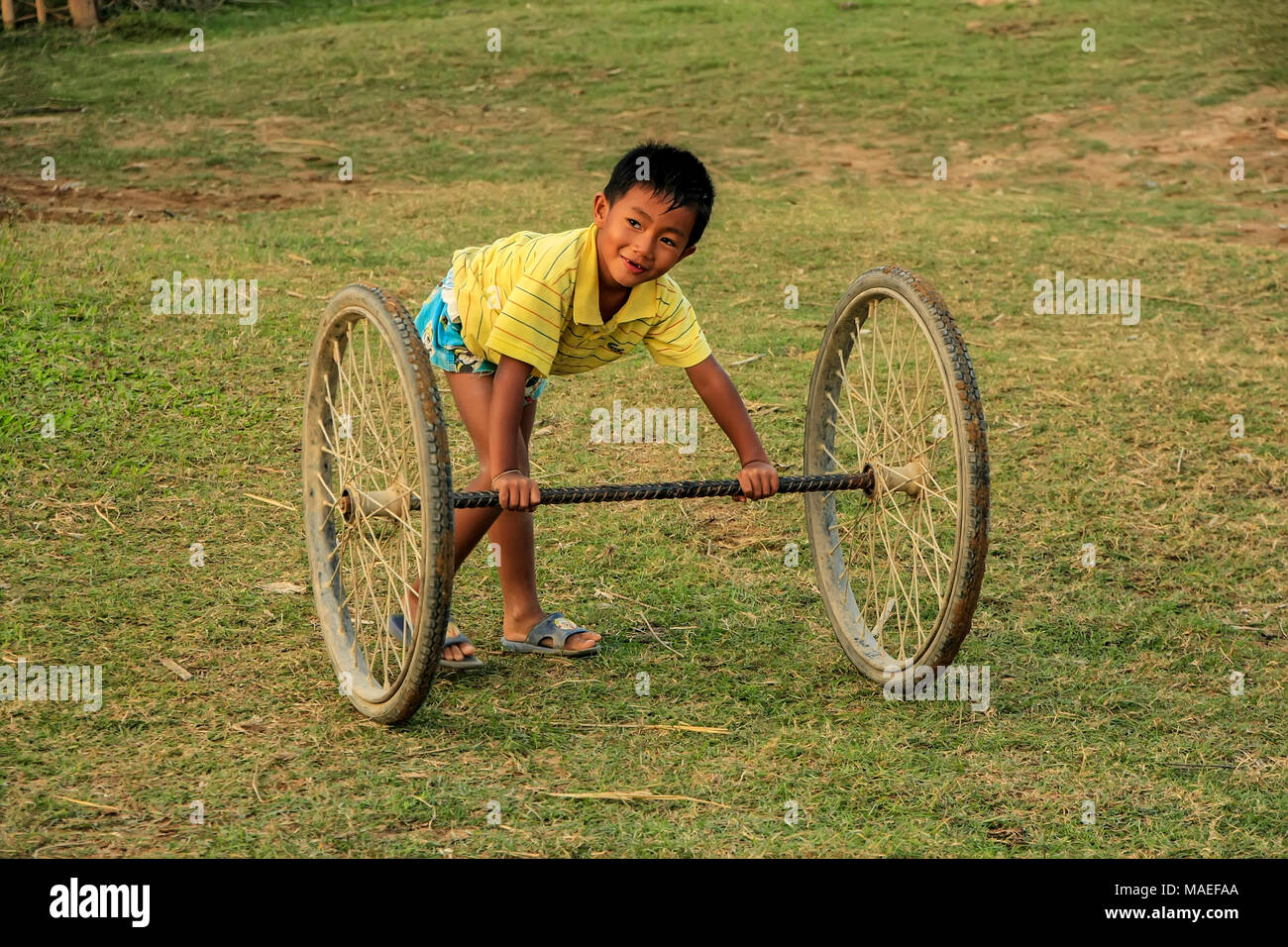 Capretto locale a giocare con le ruote in Vang Vieng, Laos. Vang Vieng è un complesso turistico-oriented cittadina in provincia di Vientiane. Foto Stock