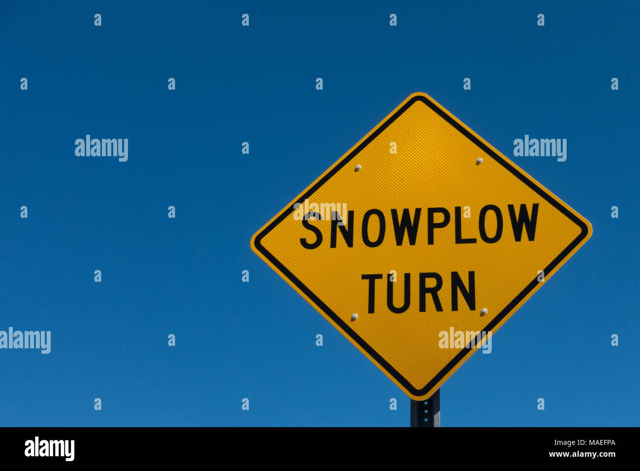 Giallo luminoso segno di avvertimento di un aratro di neve turnaround avanti contro un profondo cielo blu vicino speculatore, NY USA Foto Stock