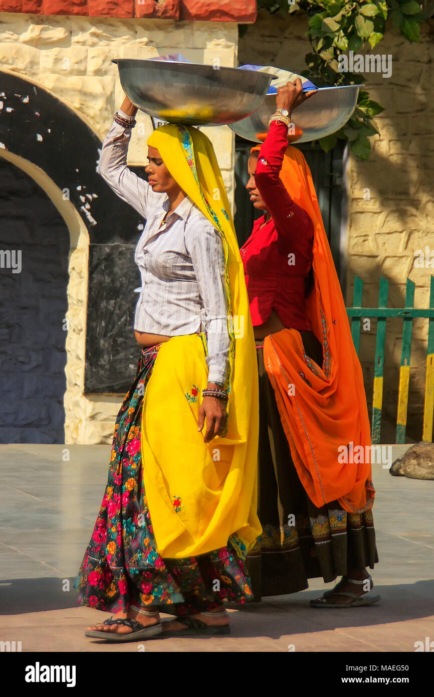 Donne locali che trasportano le benne di metallo sulle loro teste in Agra, Uttar Pradesh, India. Agra è una delle più popolose città in Uttar Pradesh Foto Stock