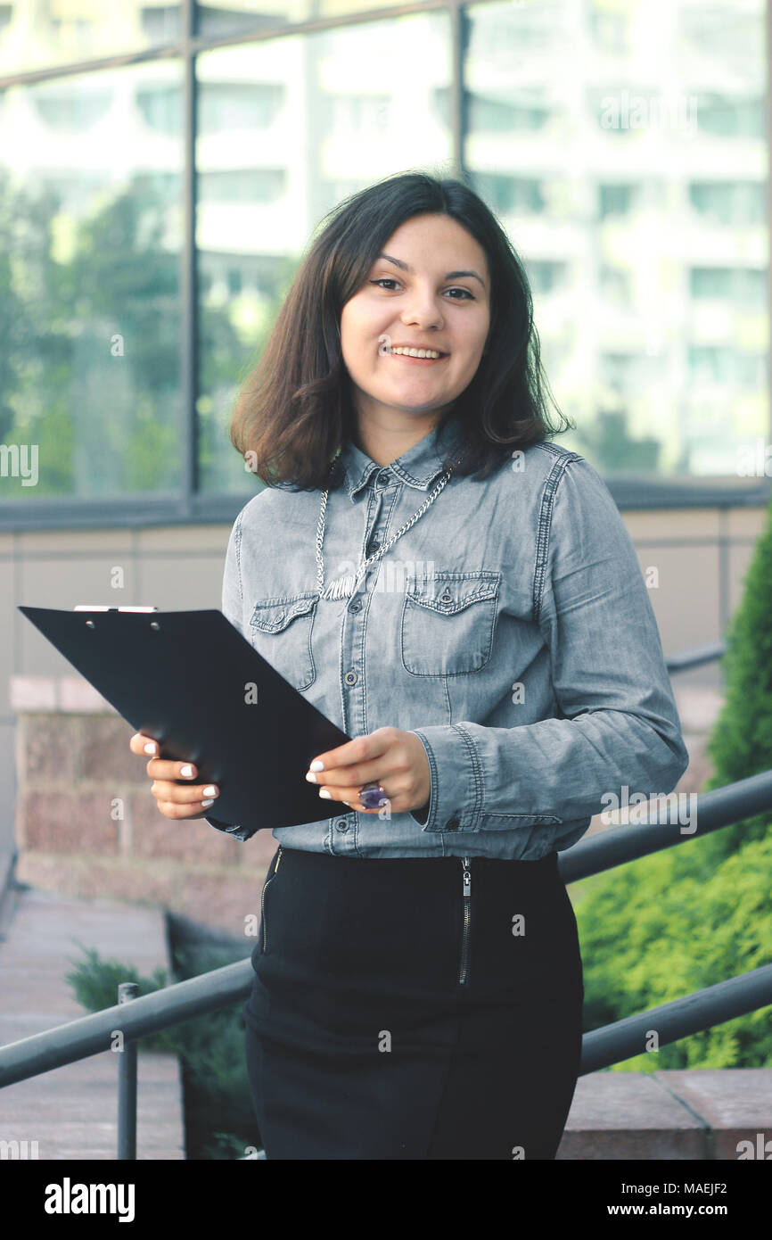 Dipendente con una clipboard stando sul balcone dell'ufficio Foto Stock