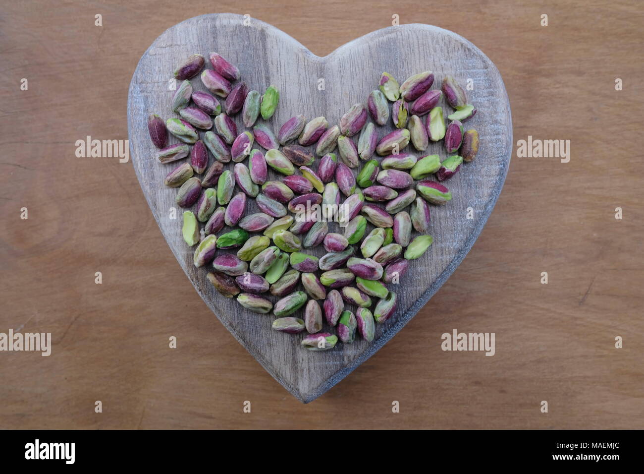 Amore i pistacchi con un cuore di legno Foto Stock